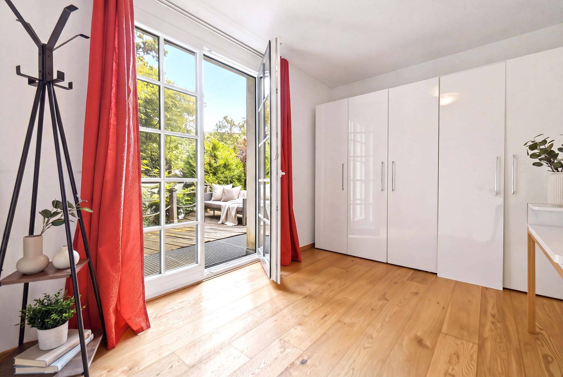 Helles Zimmer mit Holzboden, weißen Schränken und Zugang zur Terrasse, modern eingerichtet.