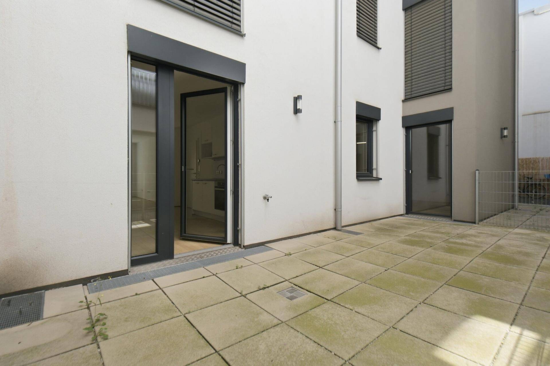 Gepflasterte Terrasse im Erdgeschoss mit direktem Zugang zum Innenbereich des Gebäudes.