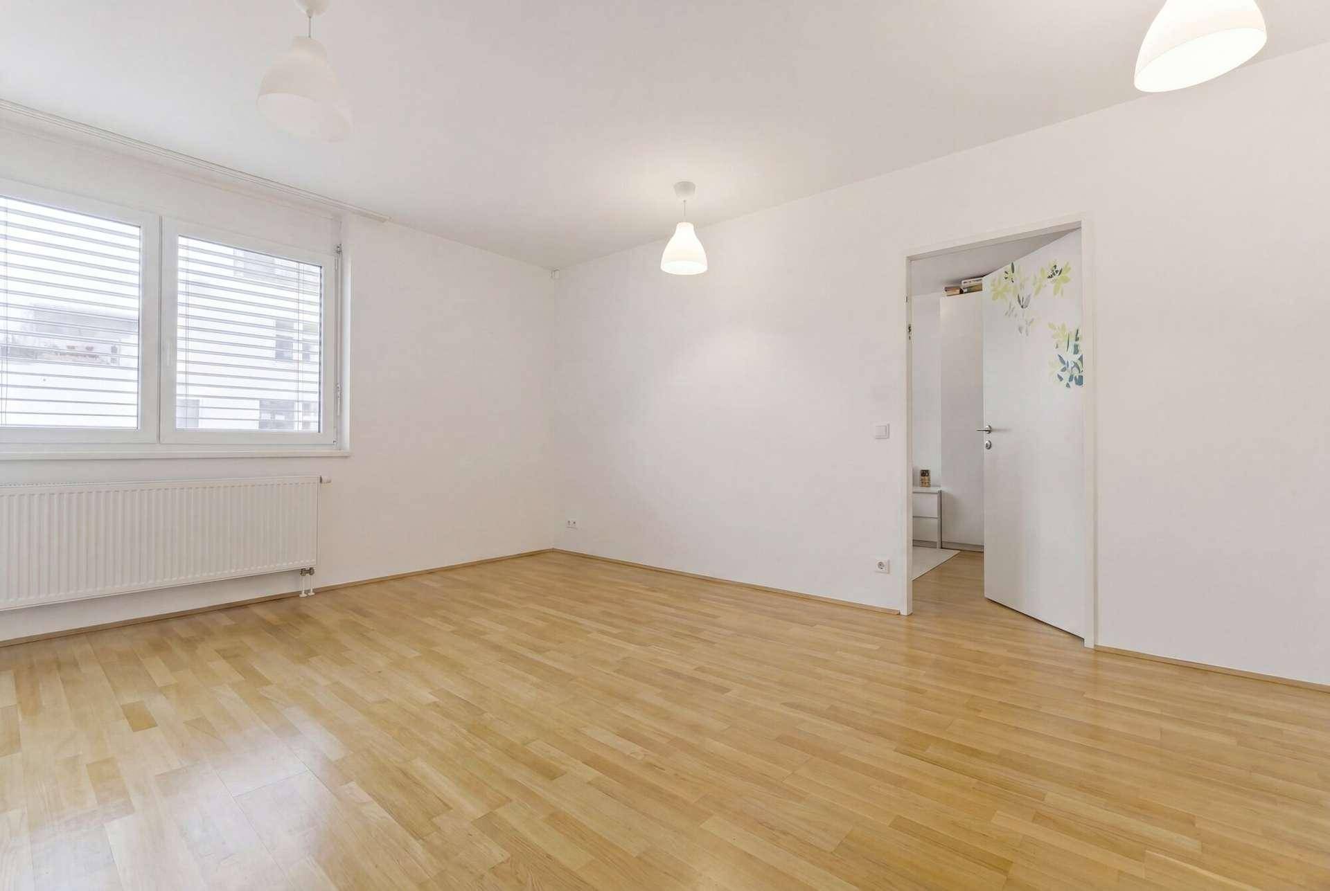Heller Raum mit Parkettboden und großen Fenstern, ideal als Wohn- oder Schlafzimmer.