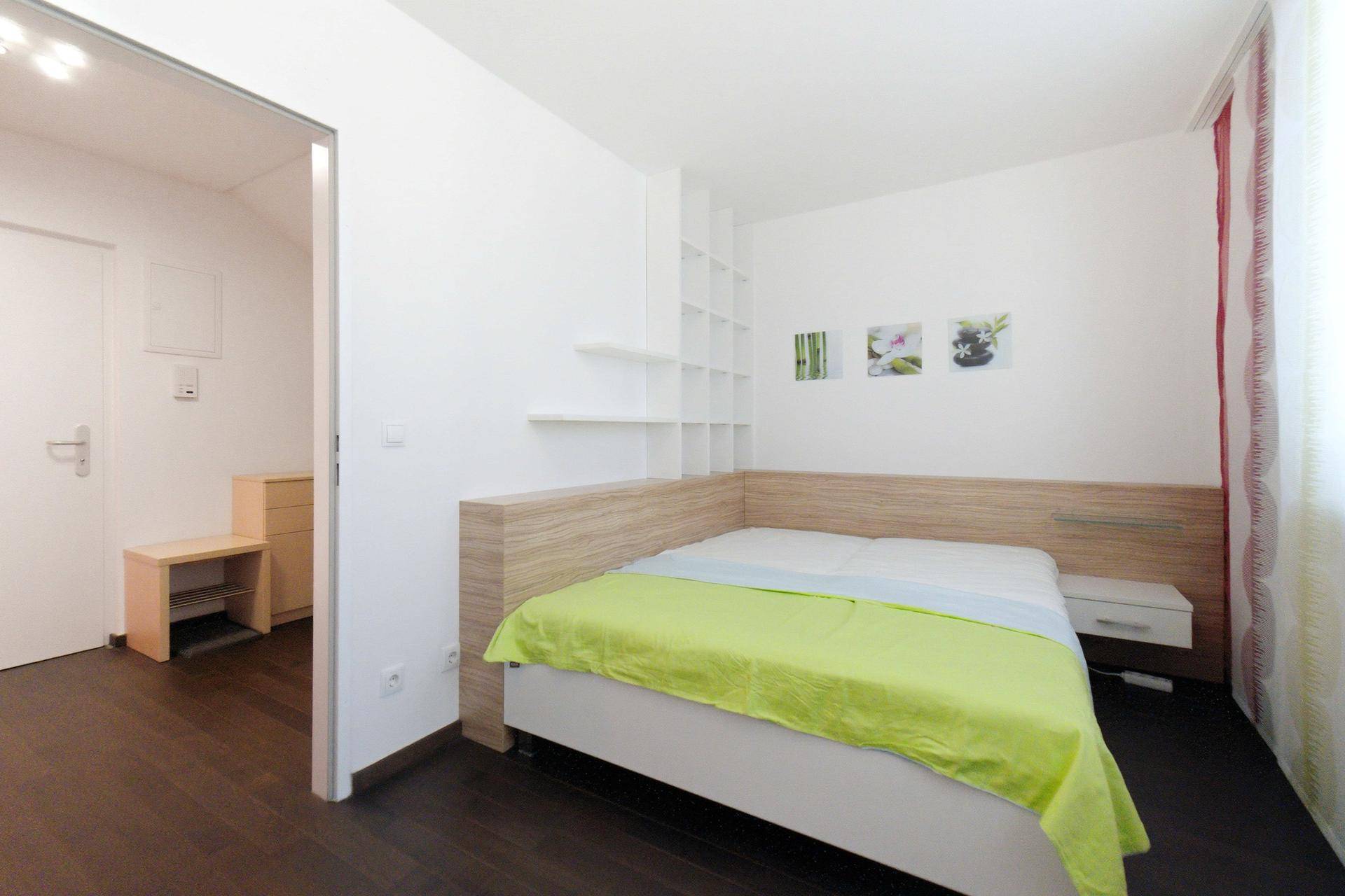 Schlafzimmer mit Holzbett und Regalen, bietet eine helle und funktionale Einrichtung.