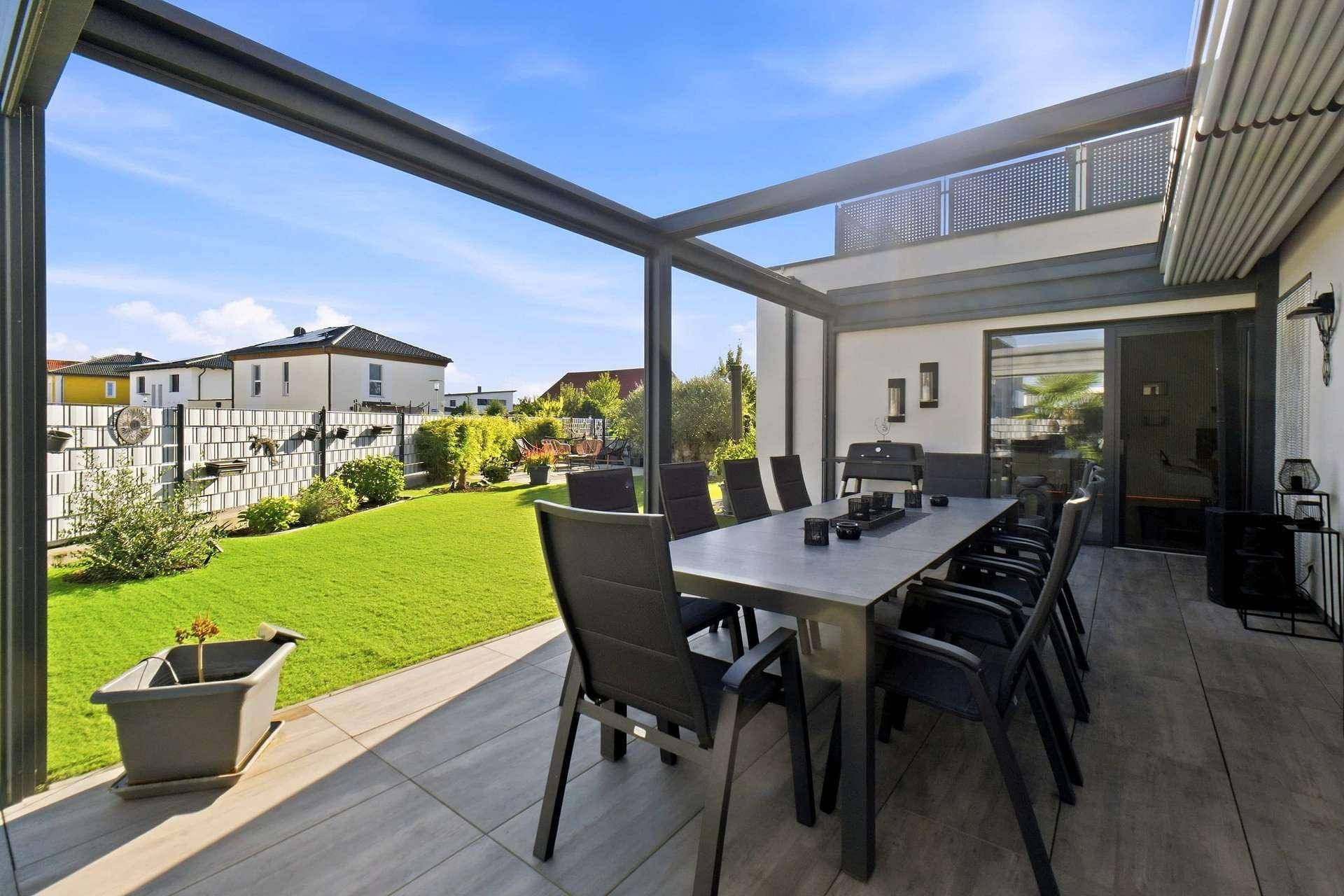 Überdachte Terrasse mit Essbereich und Zugang zum weitläufigen Garten.