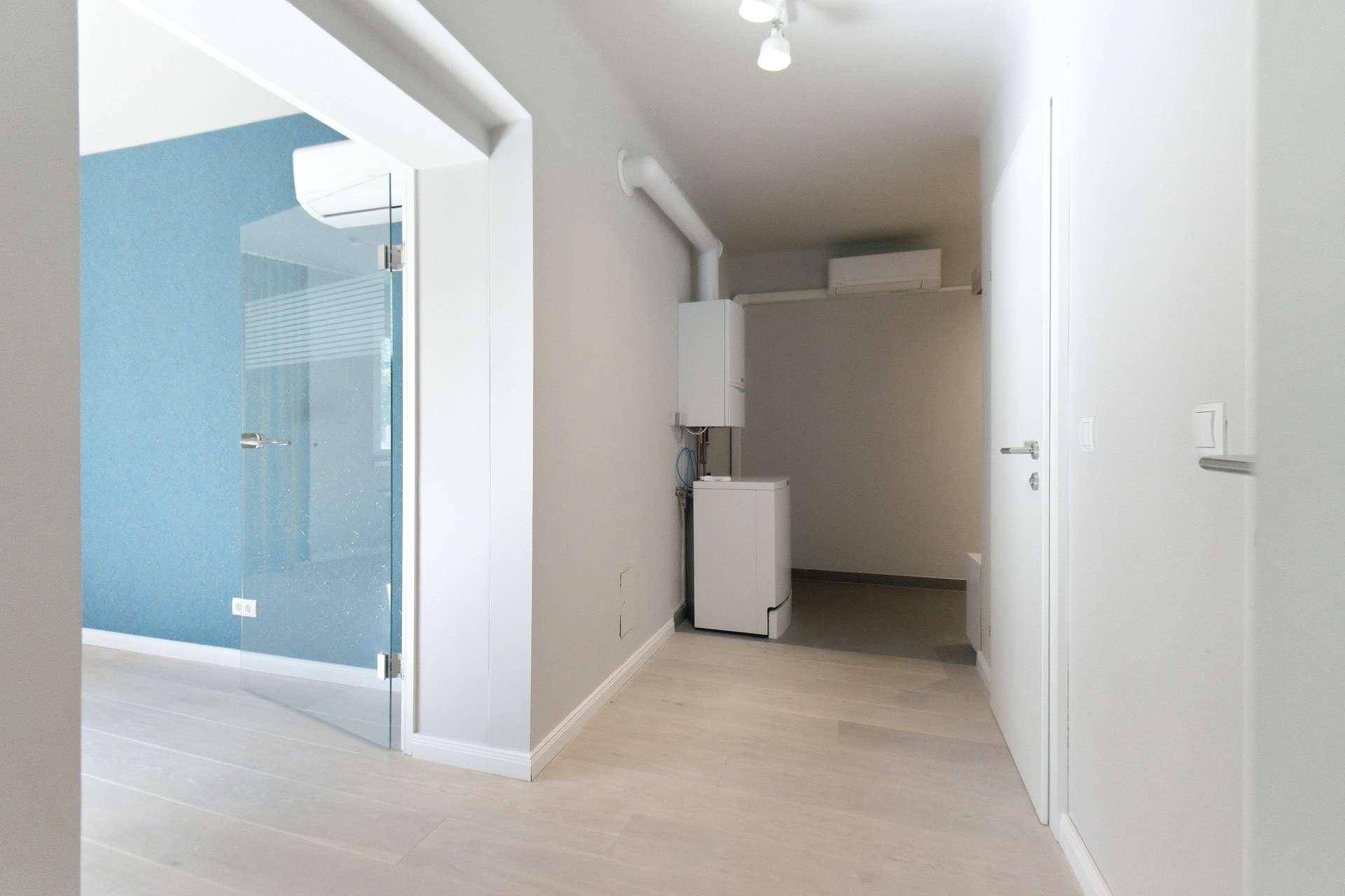 Übergangsbereich vom Flur zum Wohnzimmer mit Heizungsanlage und Glastür.
