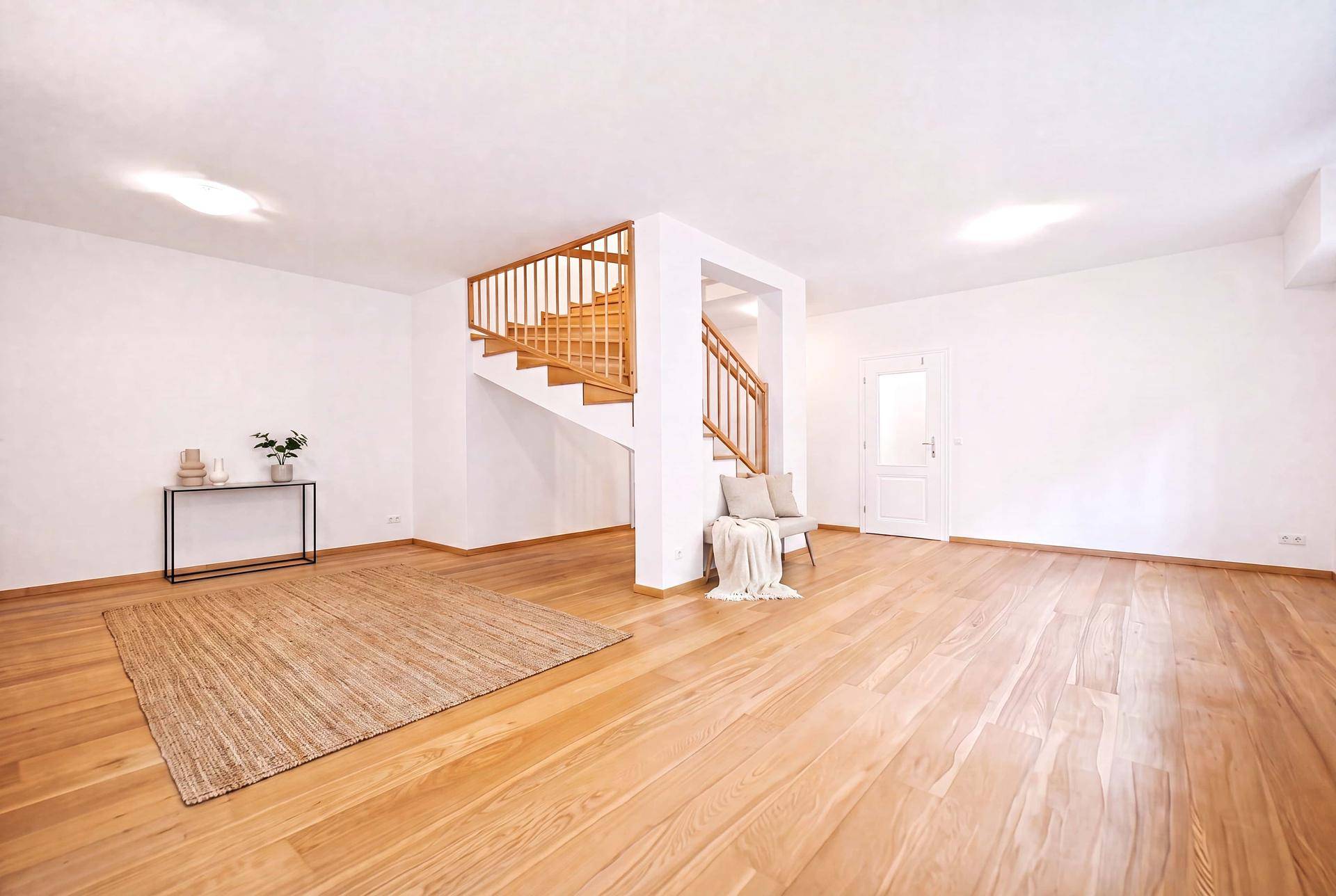 Heller Wohnbereich mit Holzboden und eleganter Holztreppe, offen und einladend gestaltet.