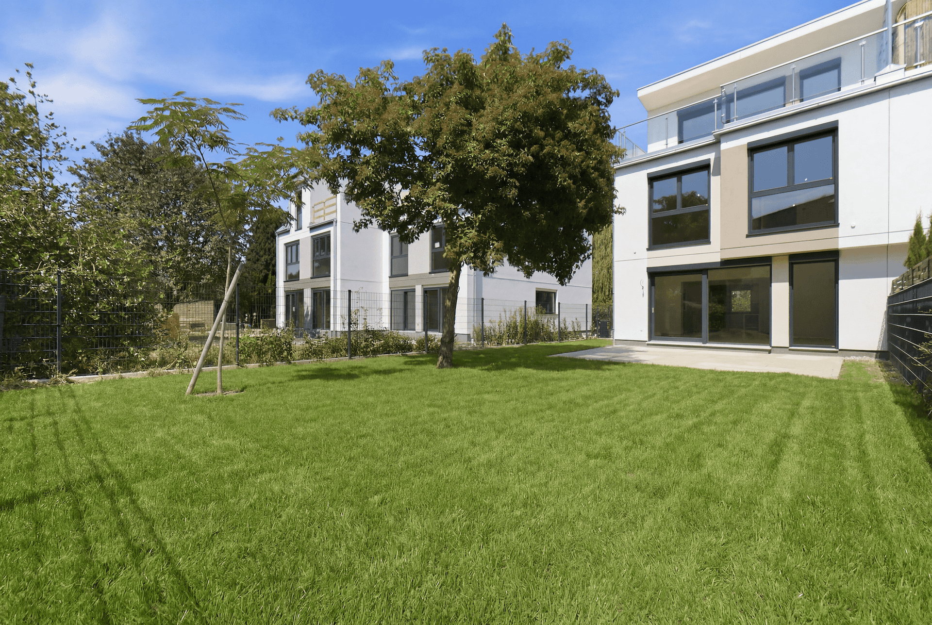 Gepflegter Gartenbereich mit Rasenfläche vor modernen Doppelhaushälften.