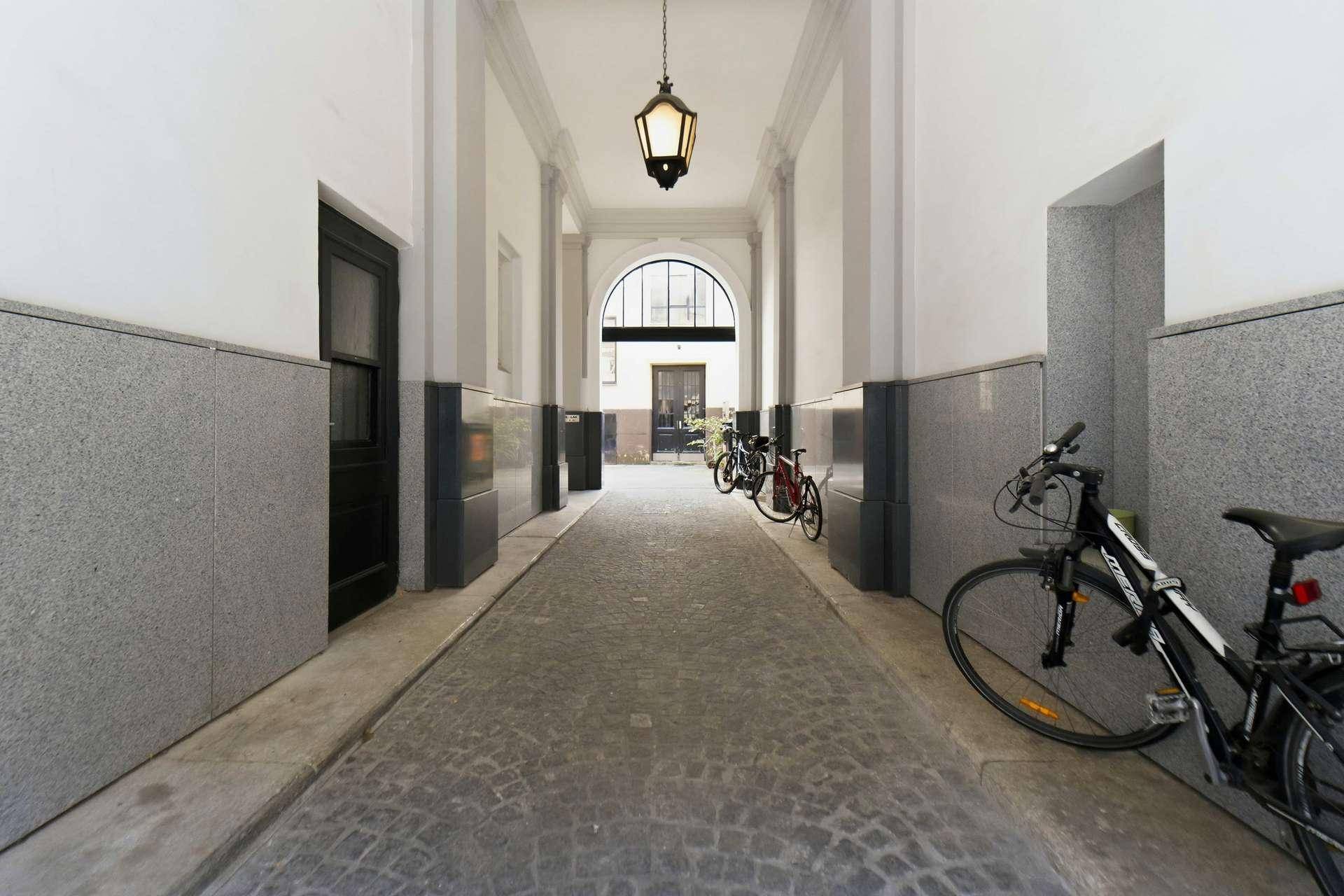 Historischer Durchgang mit Kopfsteinpflaster und Fahrrädern, der zu einem Innenhof führt.