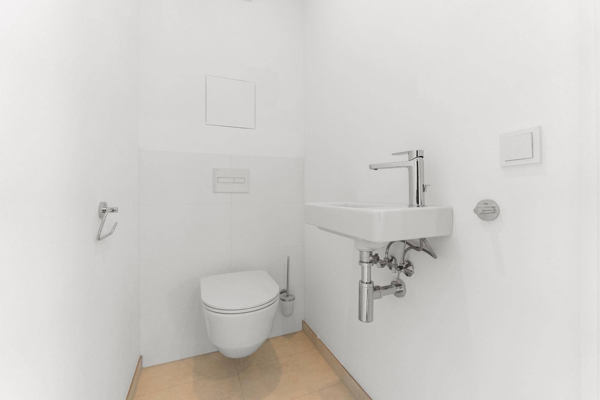 Separates Gäste-WC mit wandhängender Toilette und kleinem Handwaschbecken.