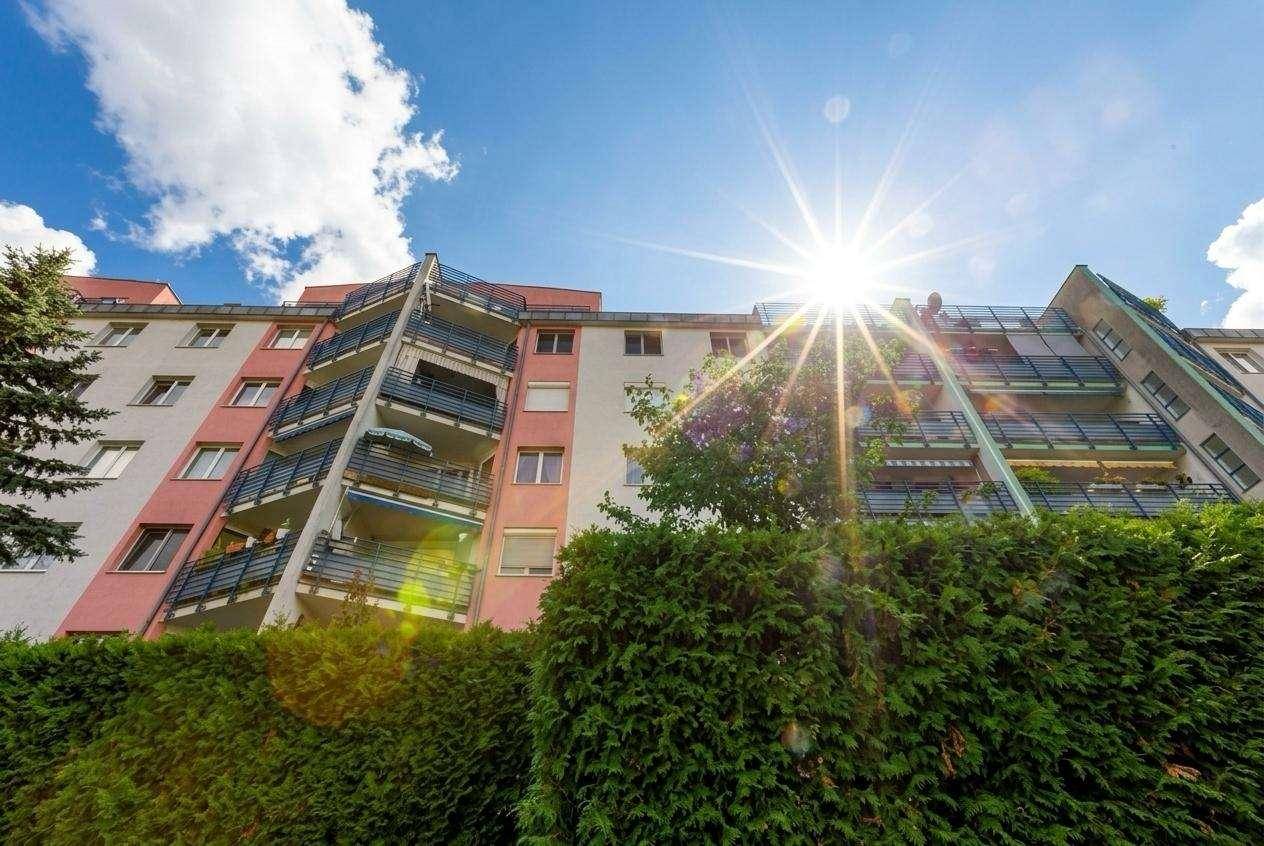 Sonnenverwöhntes Mehrfamilienhaus mit farbiger Fassade und zahlreichen Balkonen.