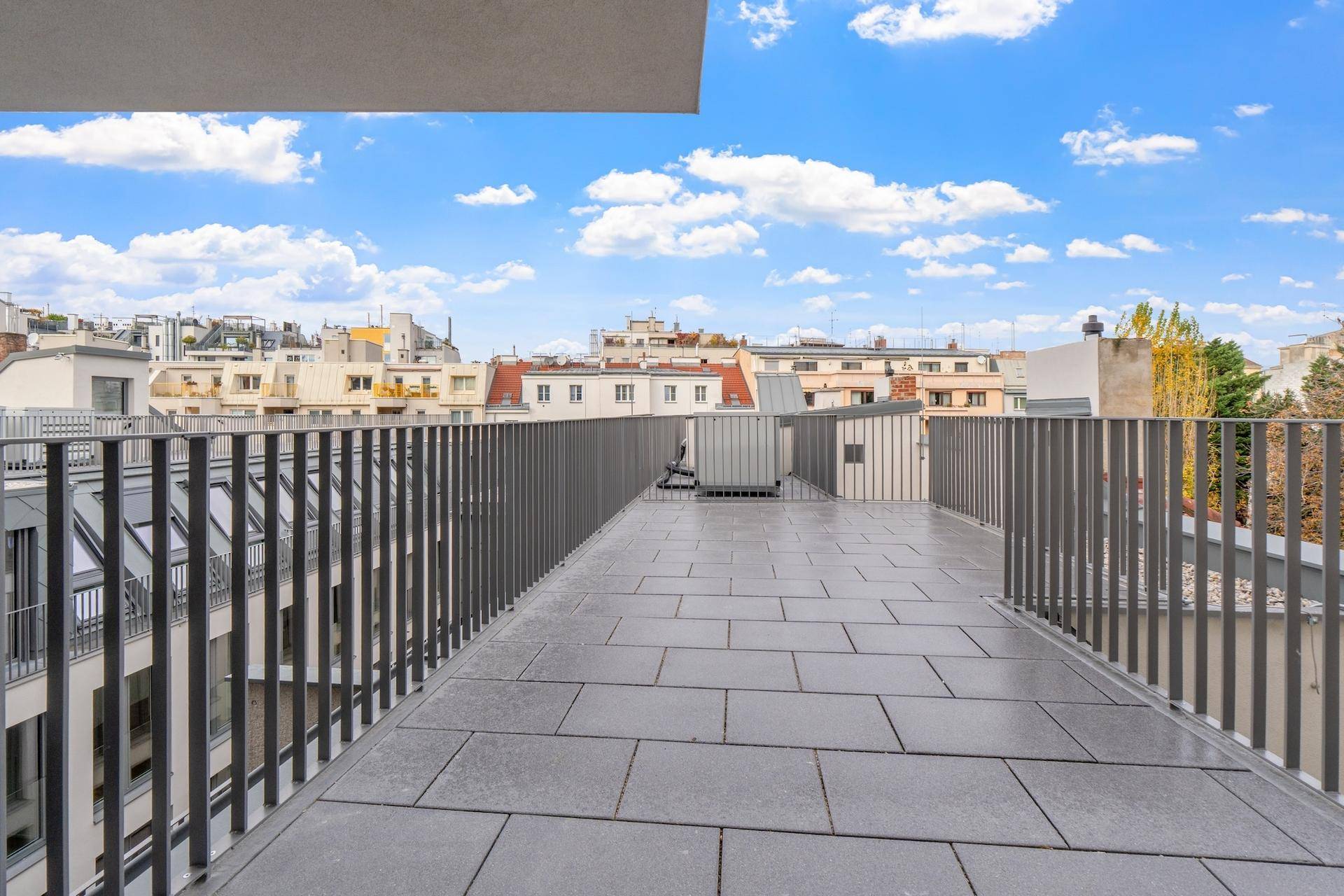 Geräumige Dachterrasse mit Fliesenboden und weitem Blick über die Stadt.