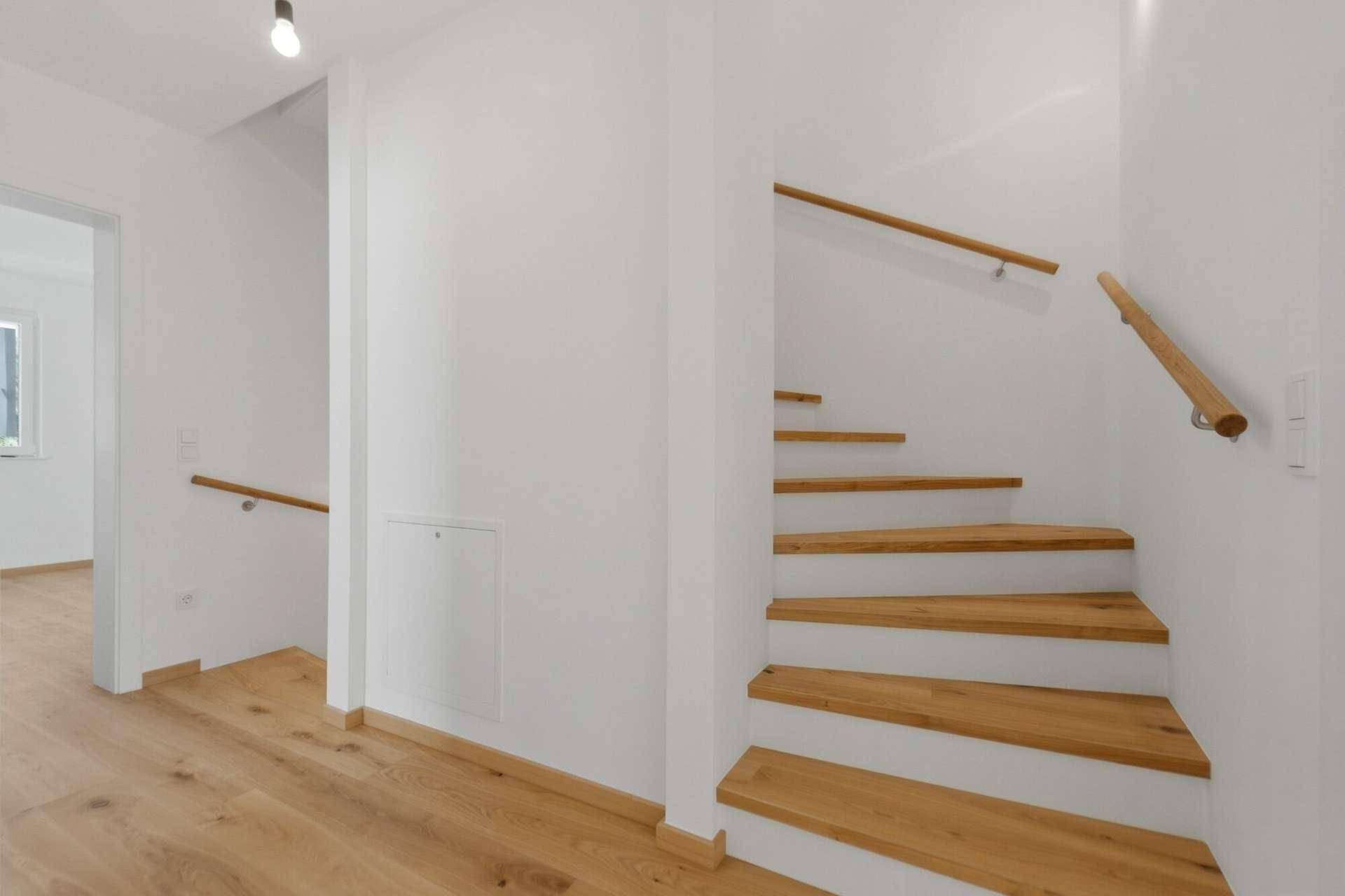 Heller Flur mit Holztreppe und Parkettboden, der die verschiedenen Ebenen verbindet.