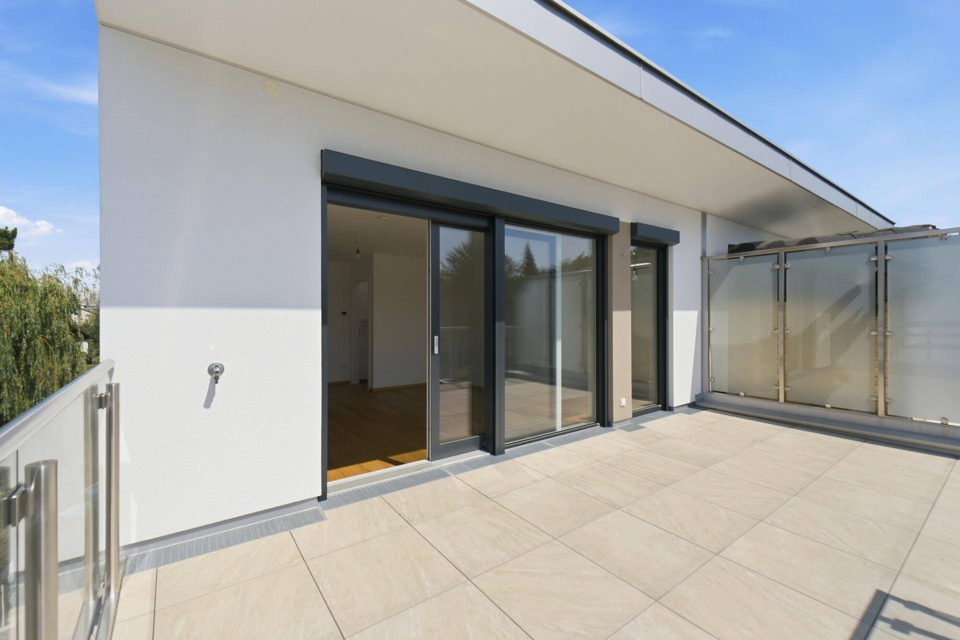 Großer Balkon mit Fliesenboden und Schiebetüren, der viel Platz im Freien bietet.