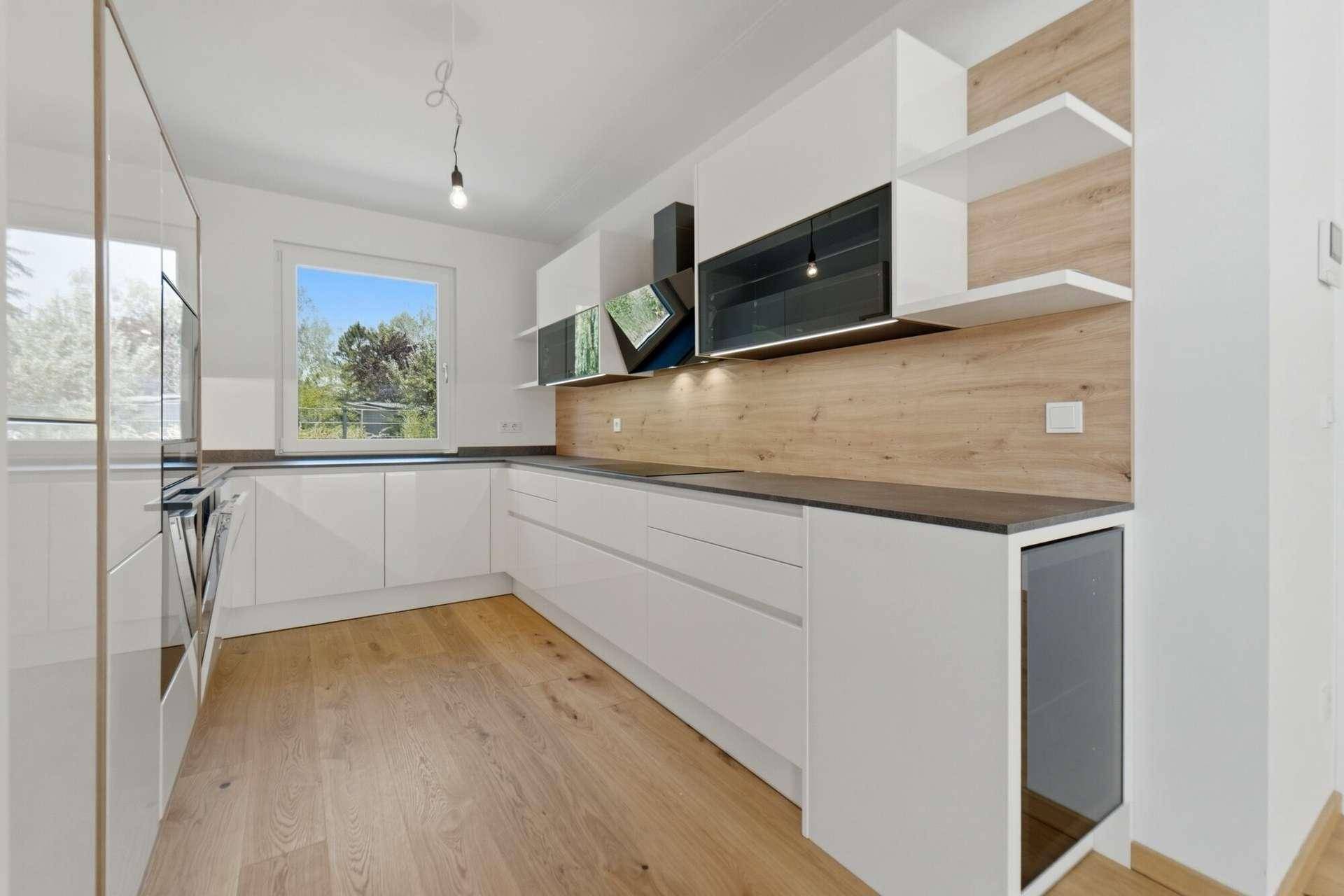 Moderne weiße Einbauküche mit Holzdetails, Induktionskochfeld und integrierten Geräten.