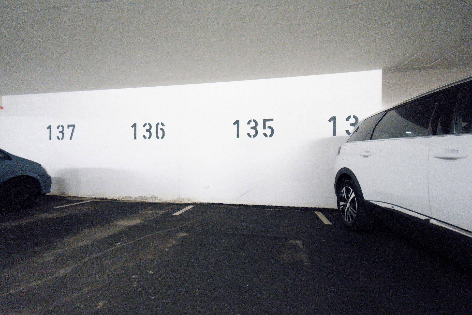 Tiefgaragenstellplatz mit Nummerierung an der Wand und einem weißen SUV.