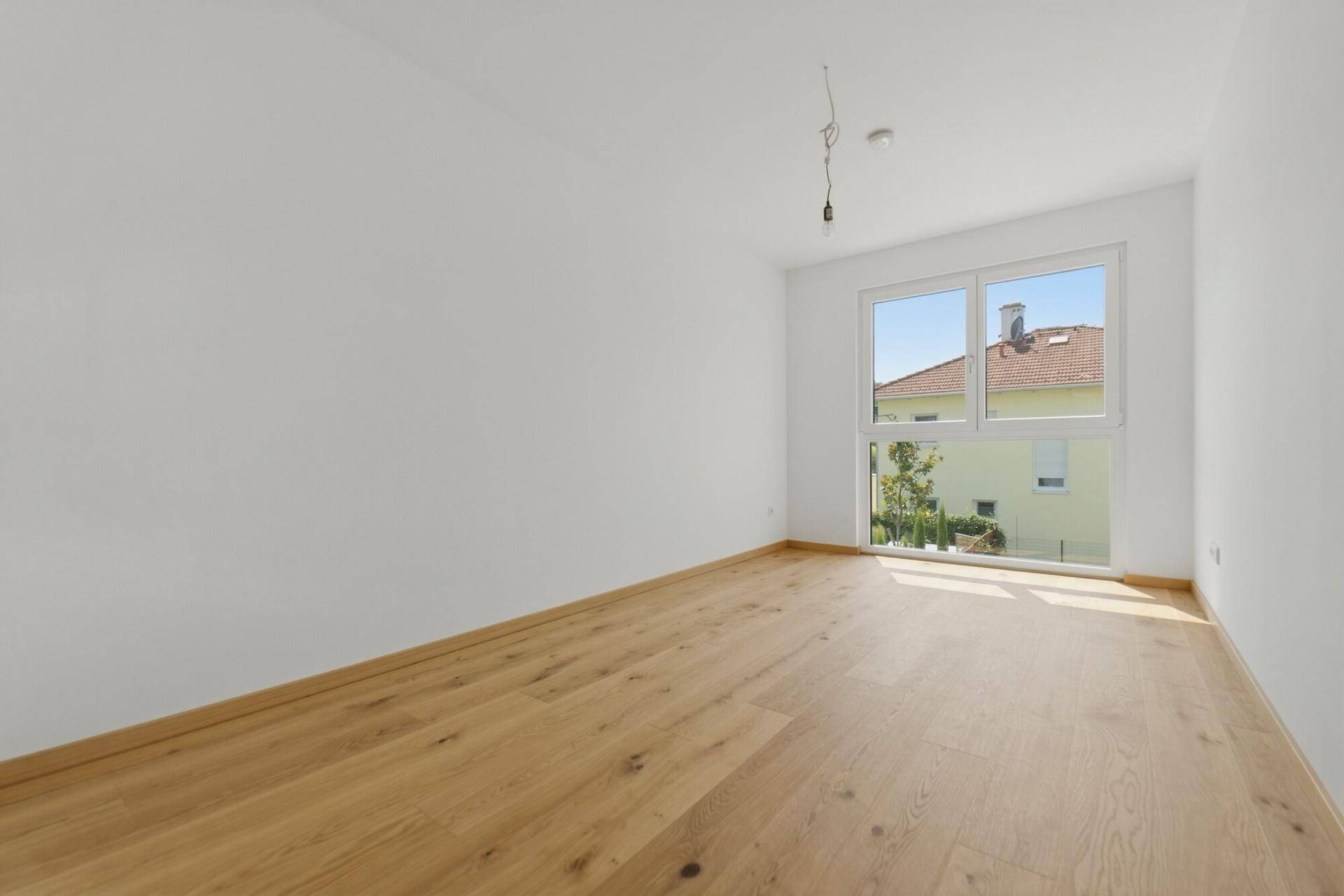 Lichtdurchflutetes Zimmer mit Holzboden und weitem Ausblick durch das große Fenster.