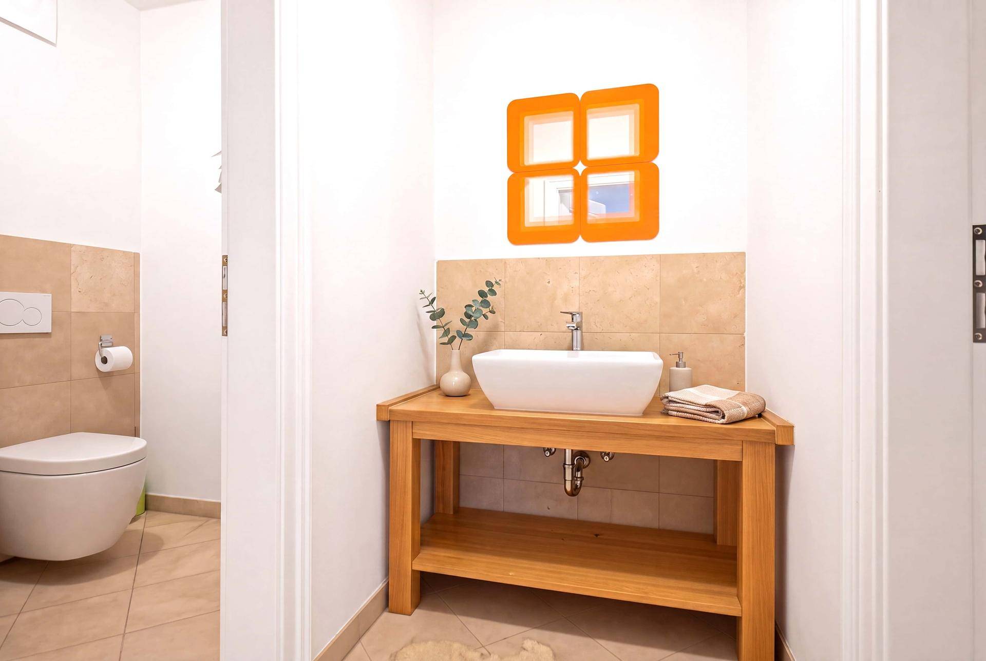 Modernes Gäste-WC mit Waschbecken auf Holzunterschrank und Wand-WC, hell und funktional.