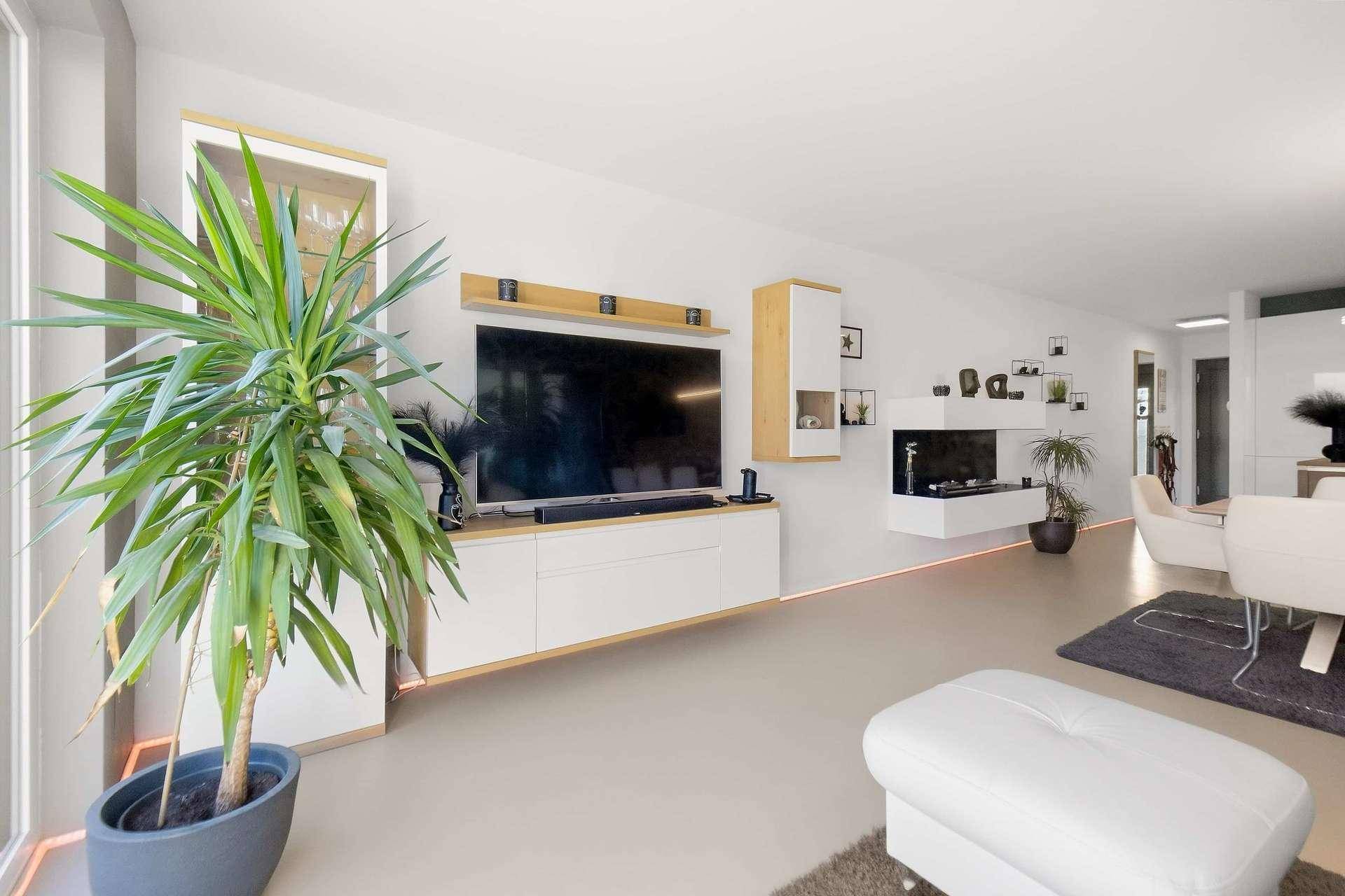 Geräumiges Wohnzimmer mit moderner Medieneinheit, indirekter Beleuchtung und stilvoller Dekoration.
