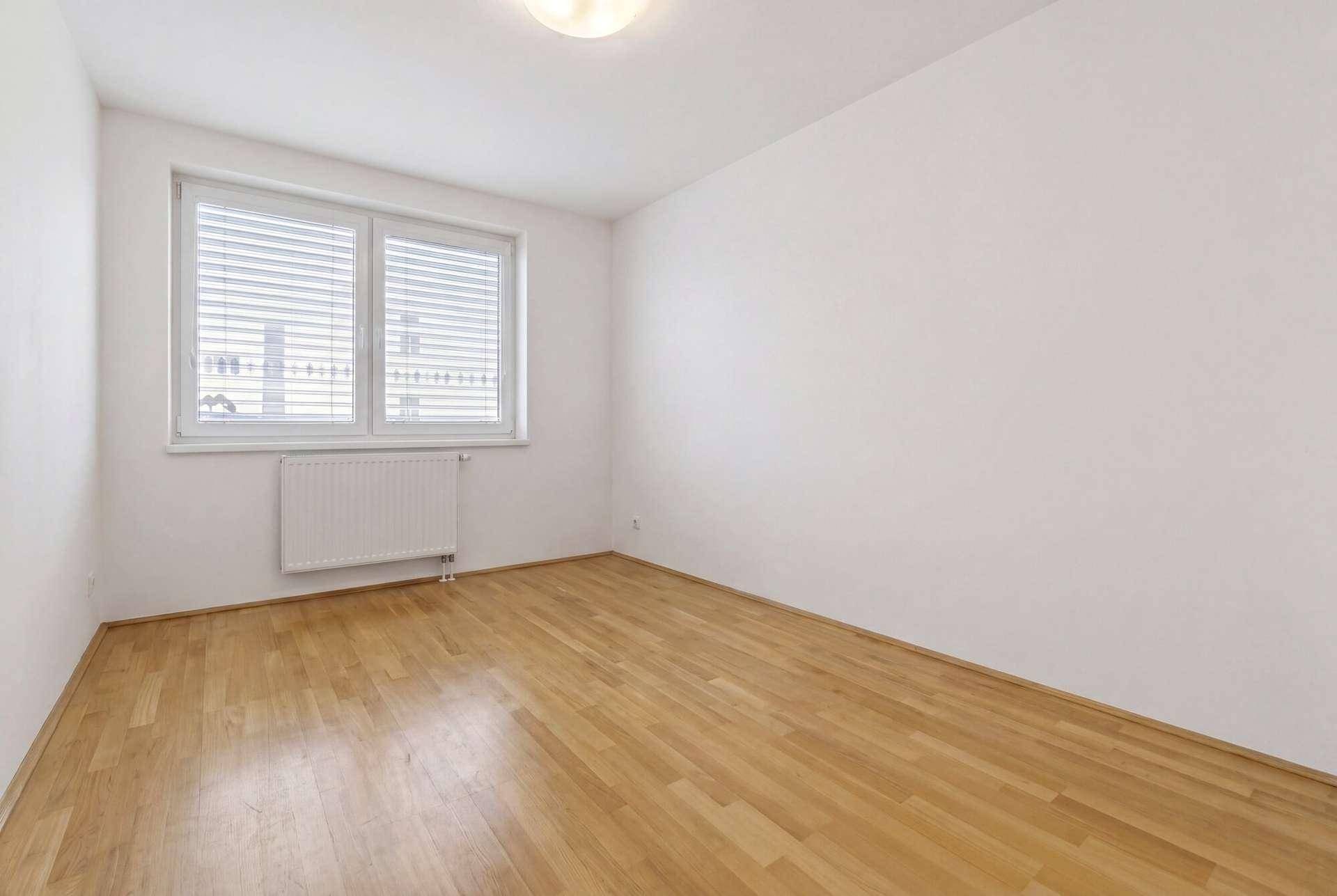 Helles Schlafzimmer mit Parkettboden und Fenster, bereit zur individuellen Gestaltung.
