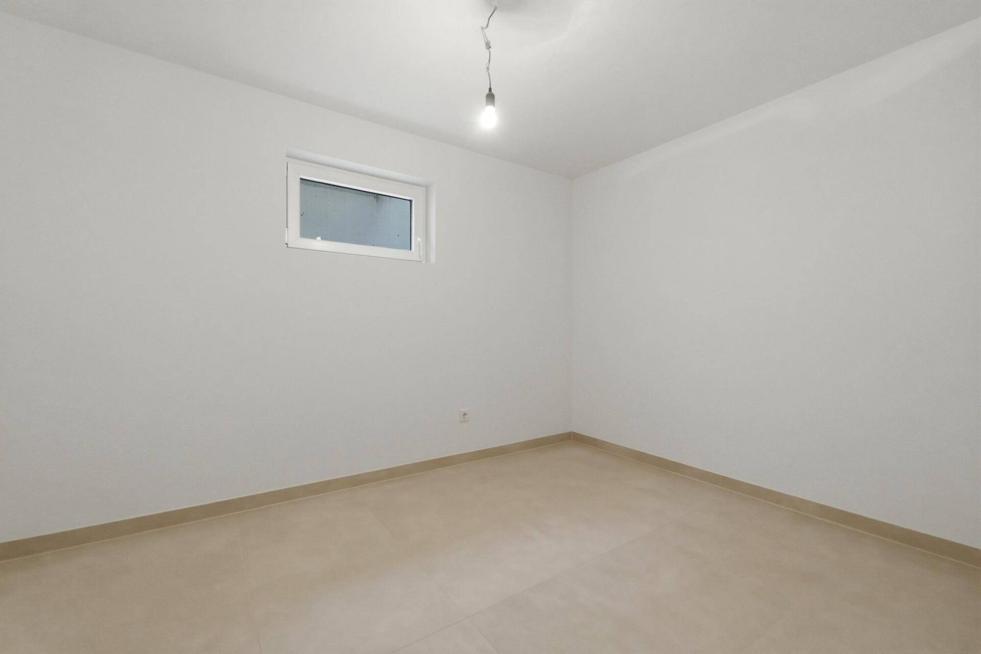 Heller Kellerraum mit Fliesenboden und einem kleinen Fenster, vielseitig nutzbar.