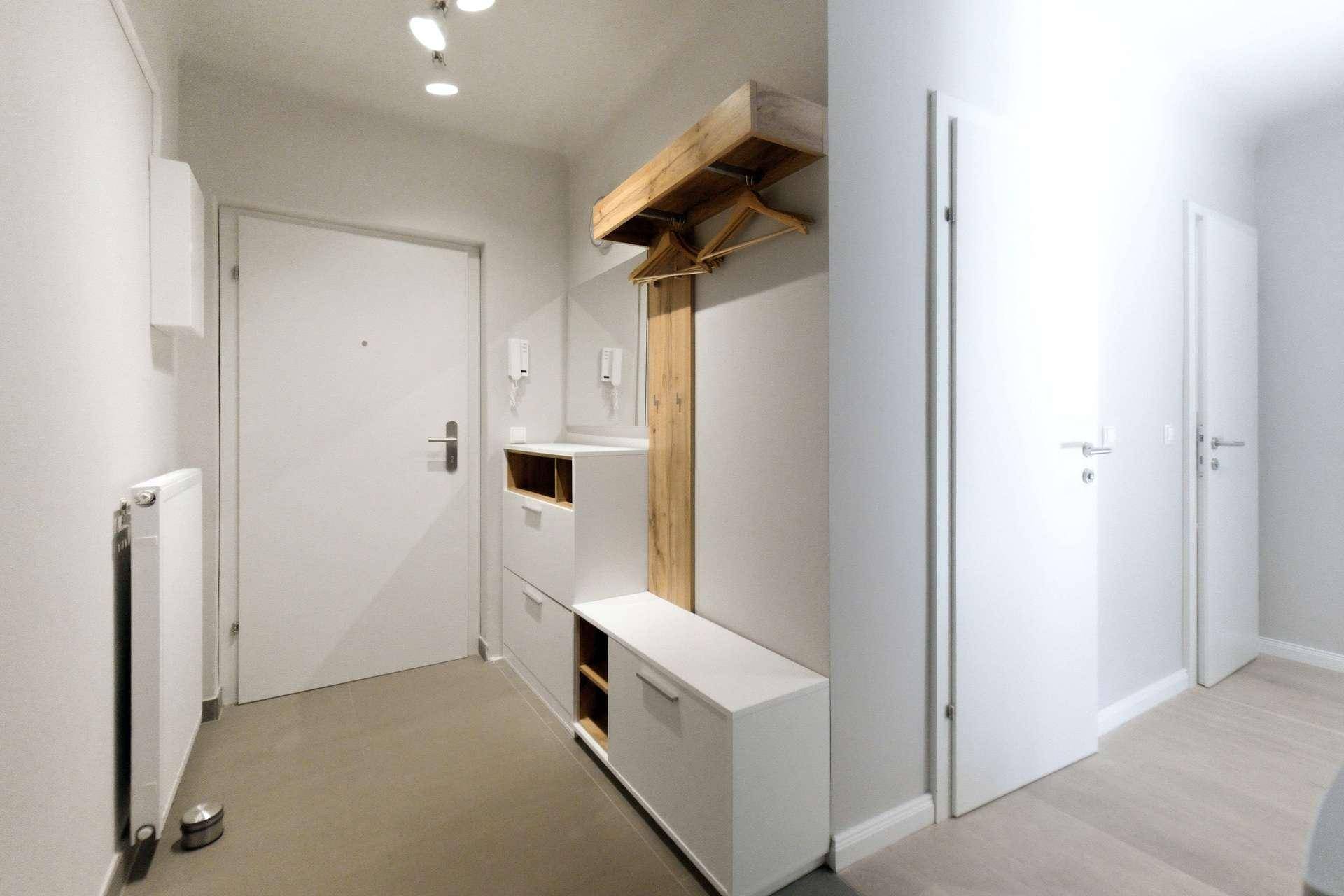 Heller Flur mit moderner Garderobe, hellem Boden und weißen Türen.