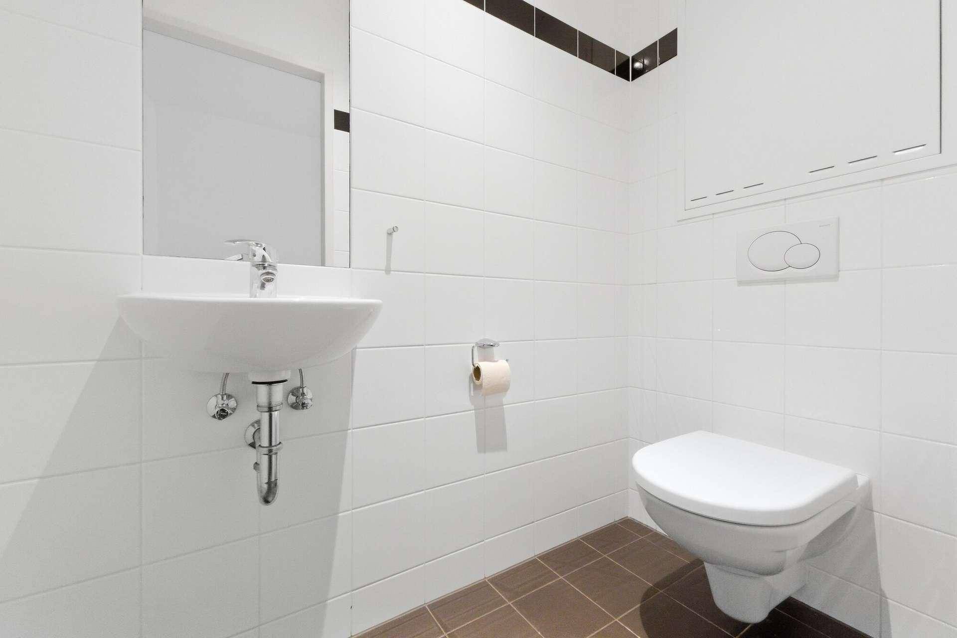 Kleines Gäste-WC mit Wand-WC und Waschbecken in schlichtem, modernem Design.