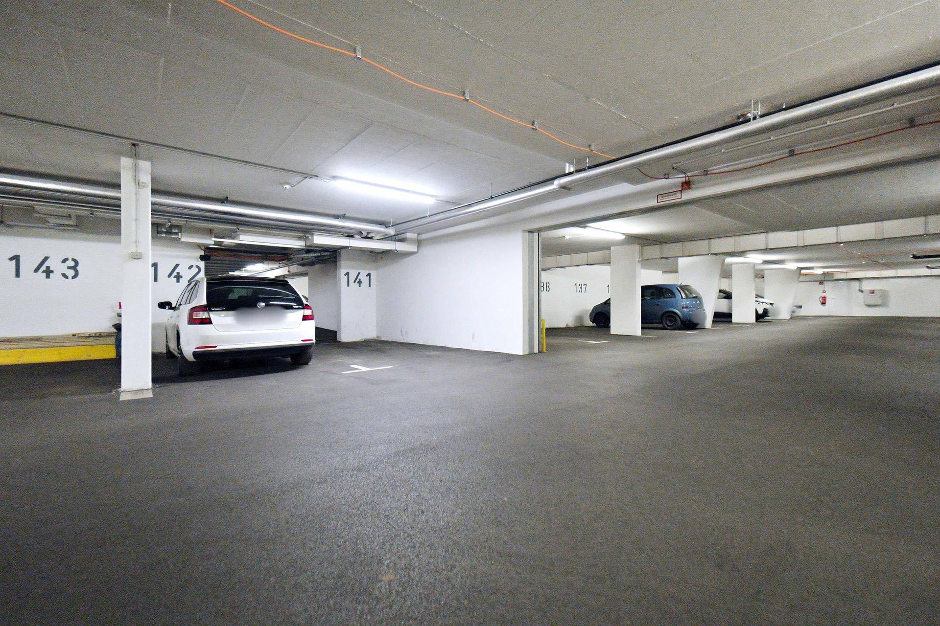 Helle Tiefgarage mit nummerierten Stellplätzen und einem weißen Kombi.