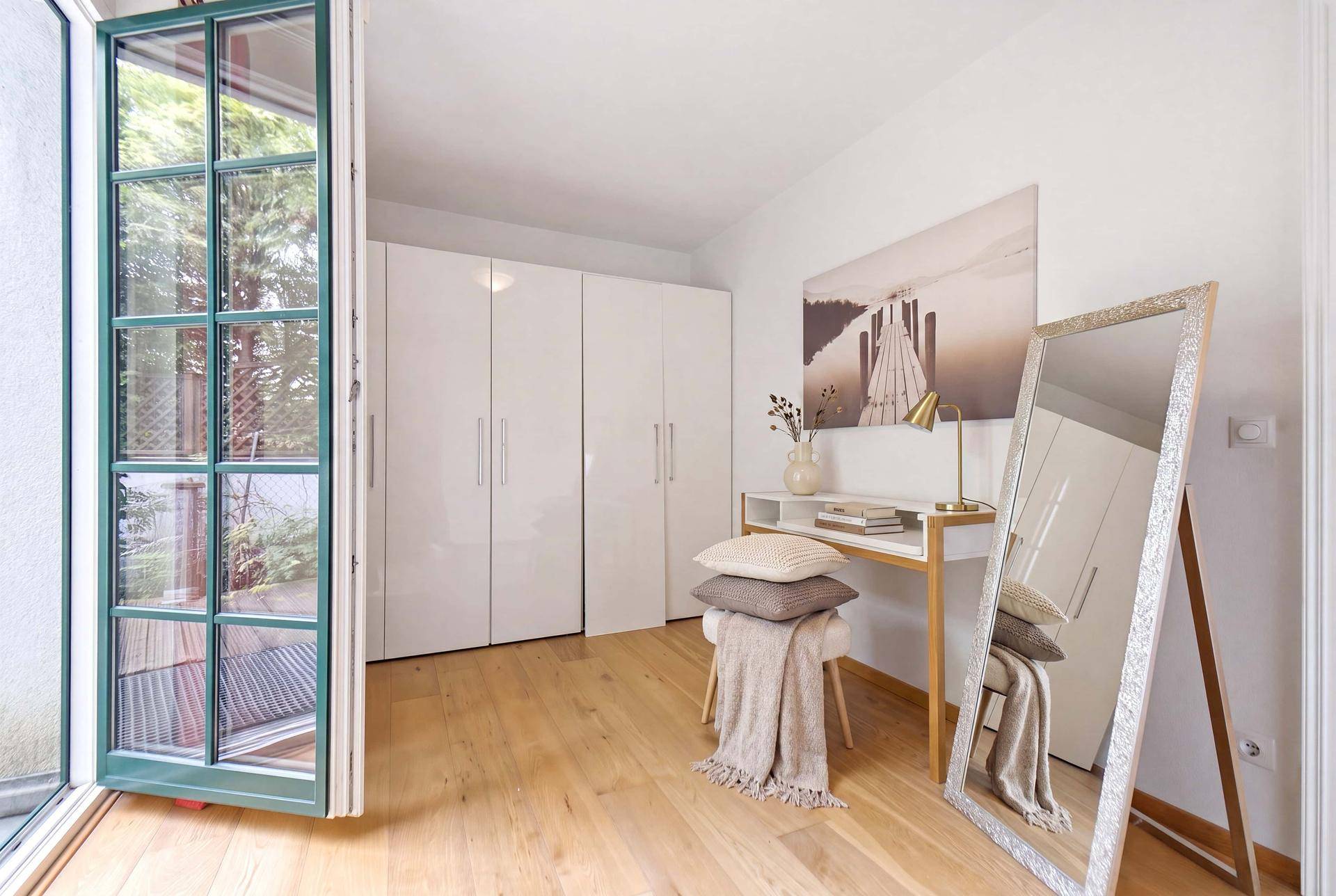 Helles Zimmer mit Holzboden, weißen Schränken und Zugang zum Außenbereich, modern eingerichtet.