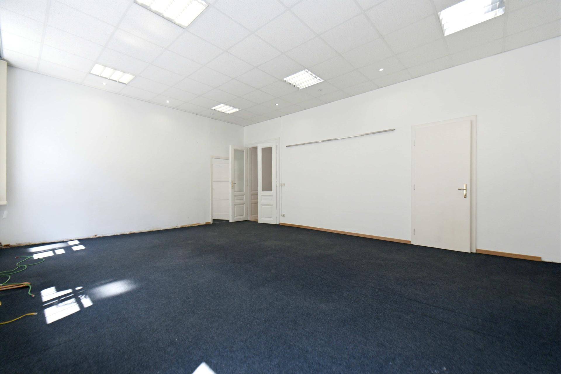 Großer, heller Raum mit dunklem Teppichboden und Doppeltüren, bietet vielseitige Nutzungsmöglichkeiten.