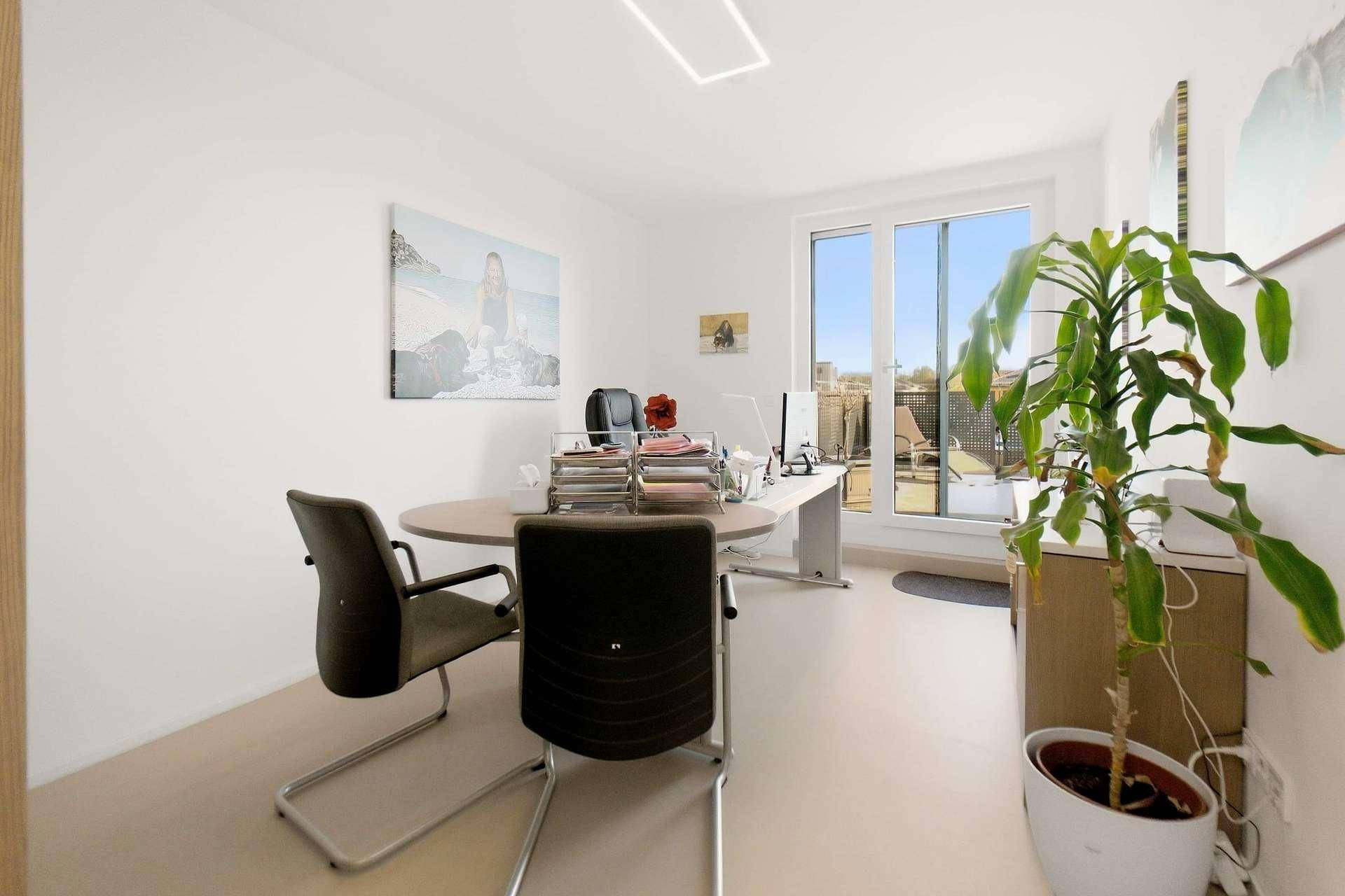 Helles Arbeitszimmer mit Schreibtisch, Bürostühlen und Zugang zu einem Außenbereich.