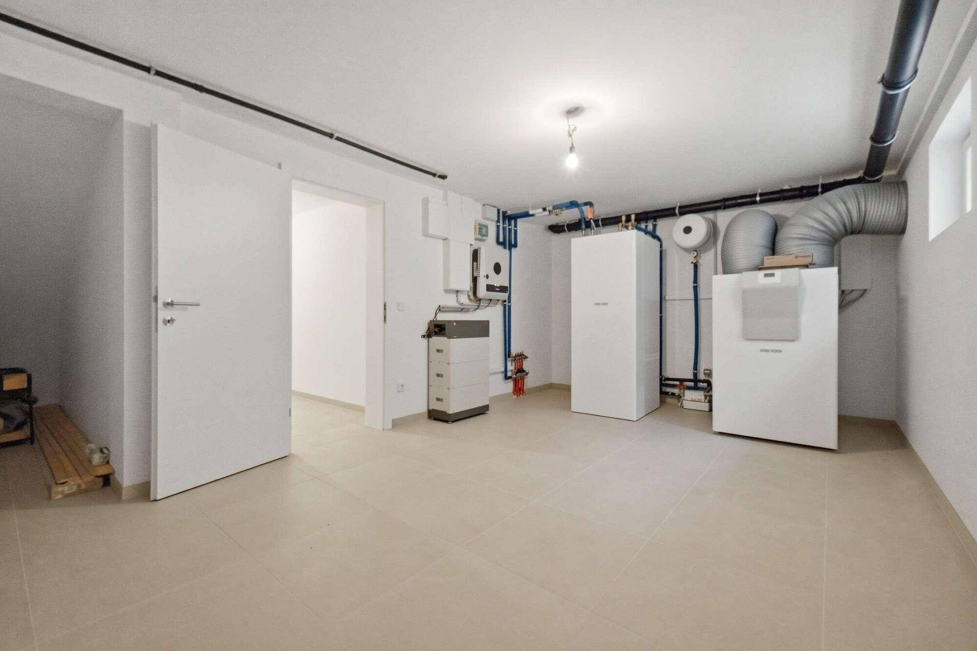 Technikraum mit modernen Heizungs- und Lüftungssystemen sowie sichtbaren Installationen.