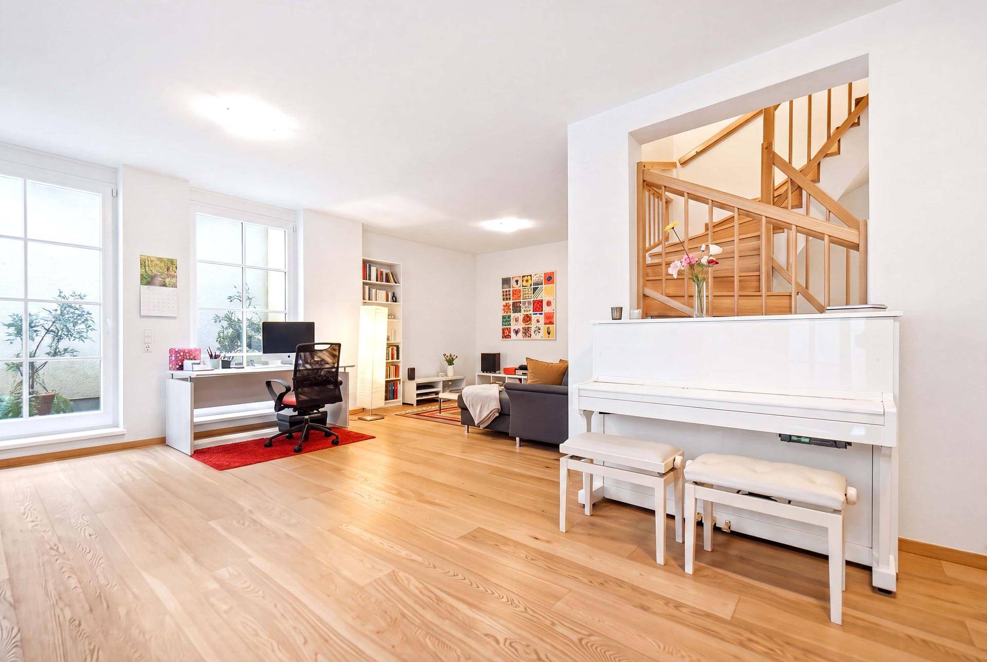 Virtuell inszenierter Wohnbereich mit Klavier, Schreibtisch und Sitzgelegenheiten, hell und modern.