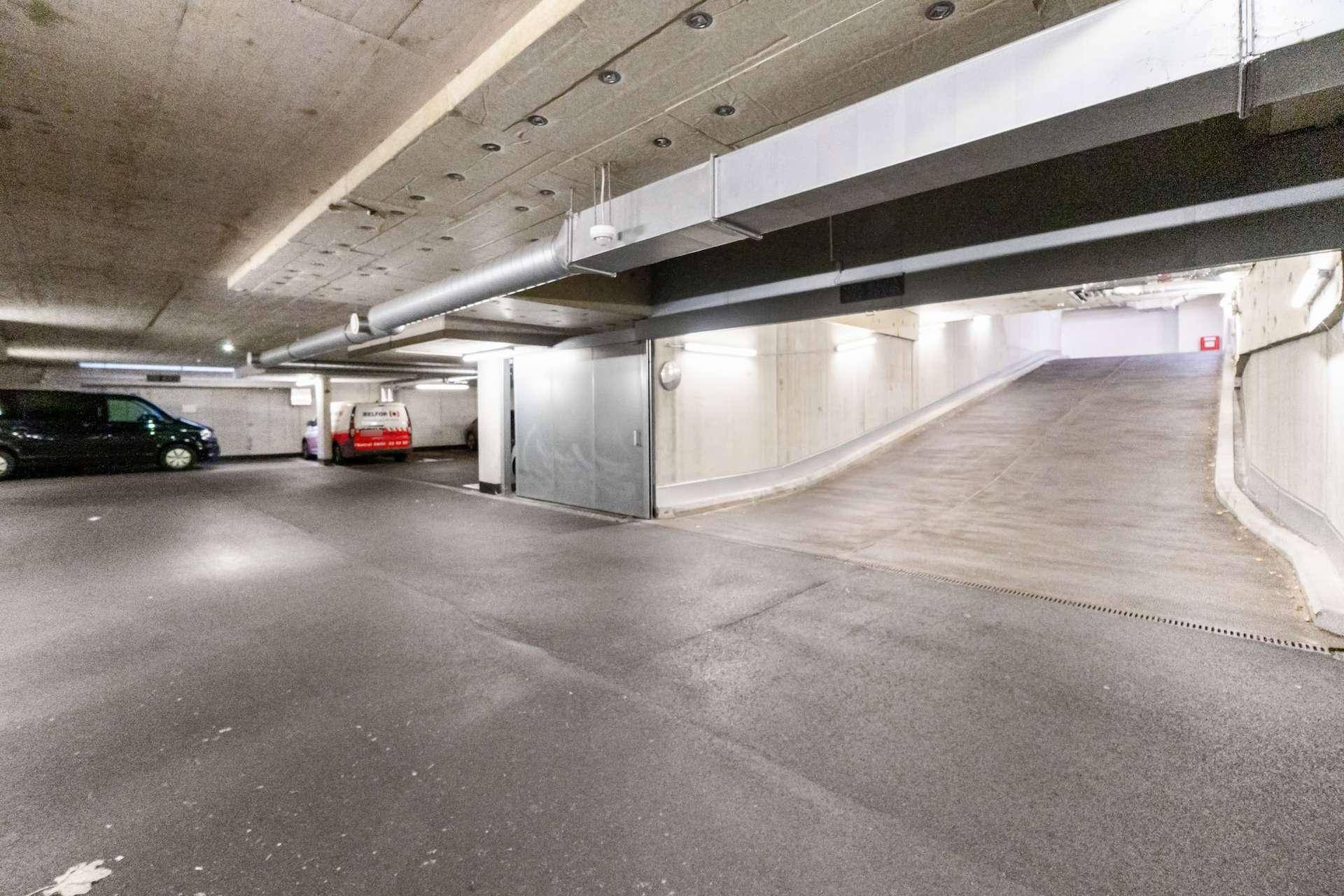 Tiefgarage mit Zufahrtsrampe und Betonwänden.