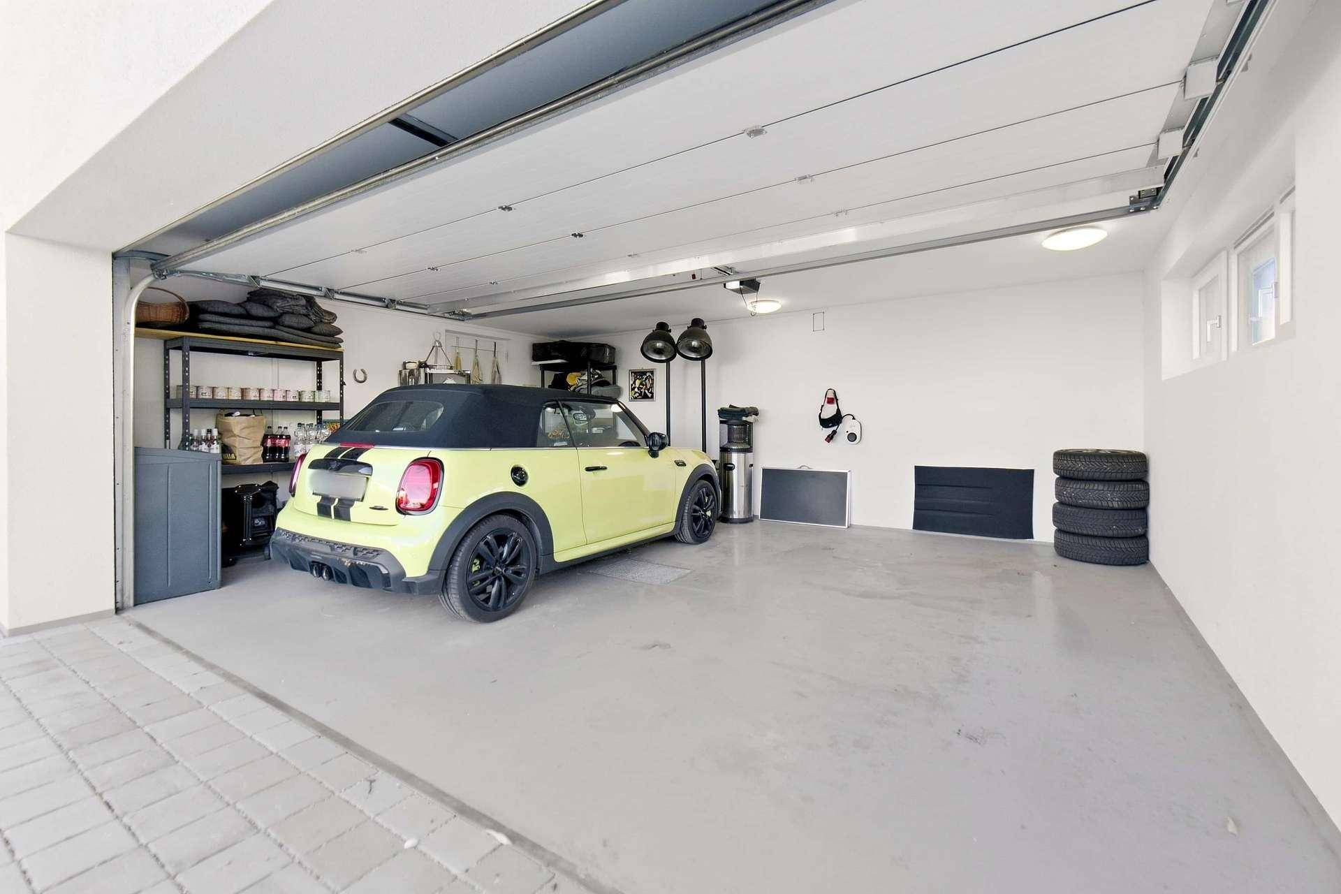 Geräumige Garage mit Stellplatz für ein Fahrzeug und Lagerregalen.