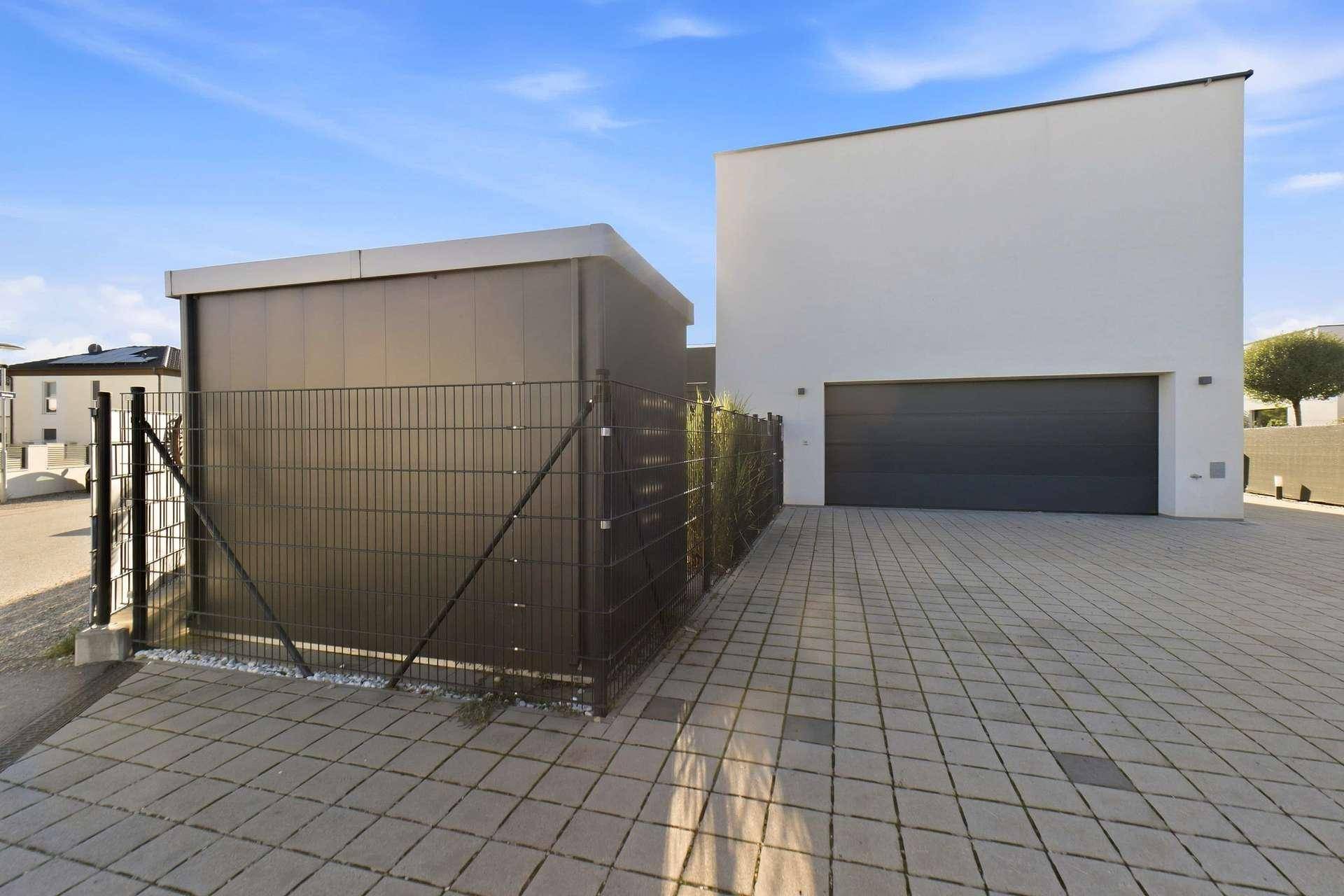 Moderne Architektur mit Garagenzufahrt und separatem Abstellraum.