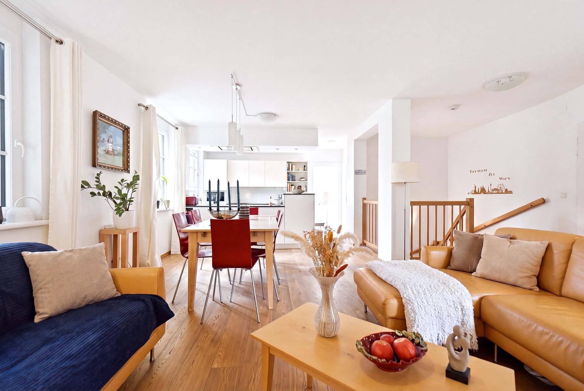 Gemütlicher Wohn-Essbereich mit Ledersofa, Holzboden und offener Küche, perfekt für entspannte Stunden.