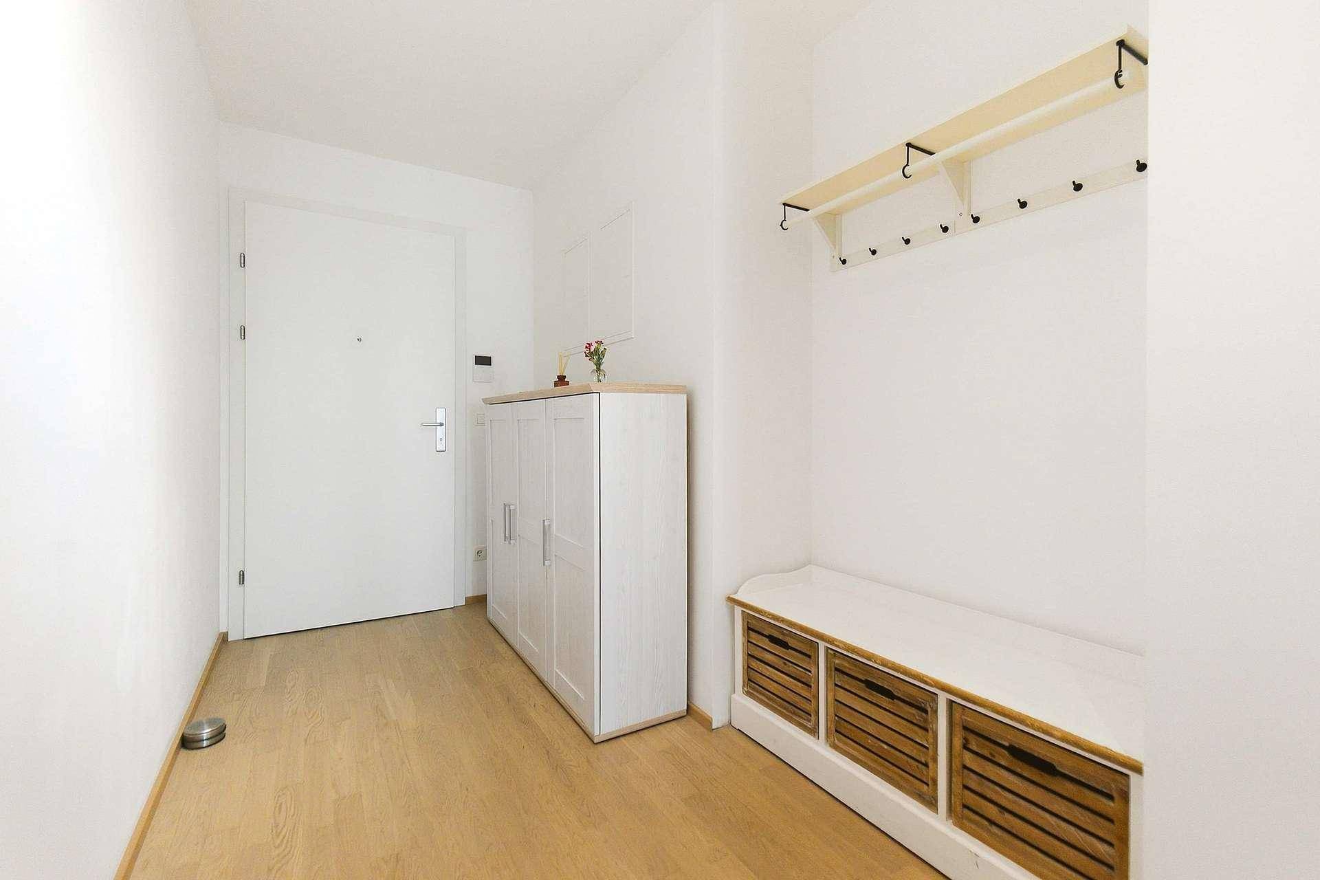 Heller Eingangsbereich mit Holzboden, Garderobe und Schuhschrank.