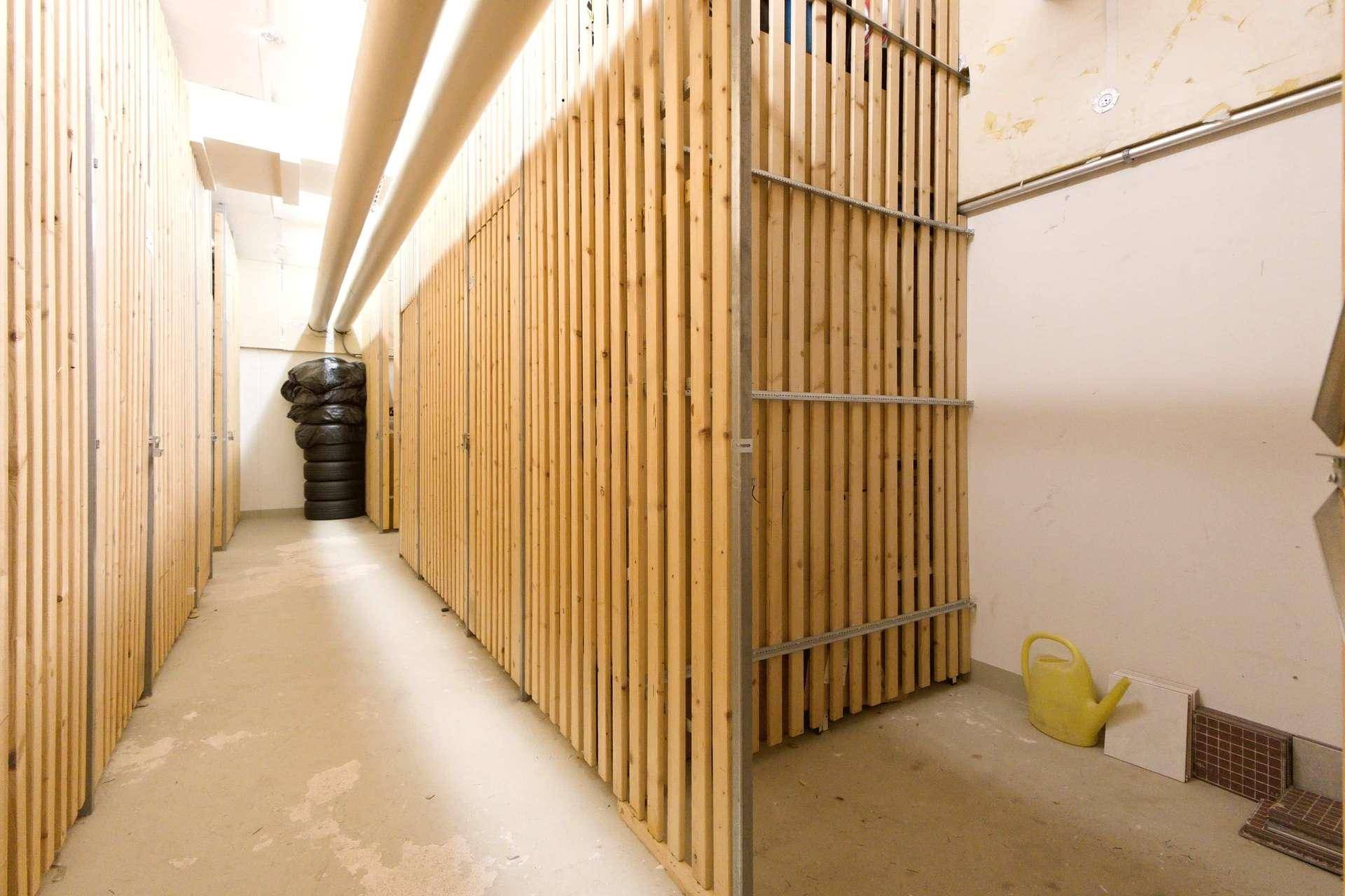 Geräumiger Abstellraum mit Holzabtrennungen und Betonboden für zusätzlichen Stauraum.
