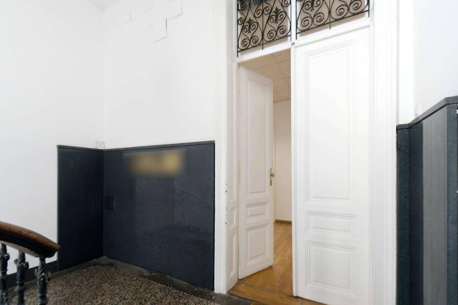 Heller Eingangsbereich einer Wohnung mit offener Tür, die den Blick auf einen Holzfußboden freigibt.