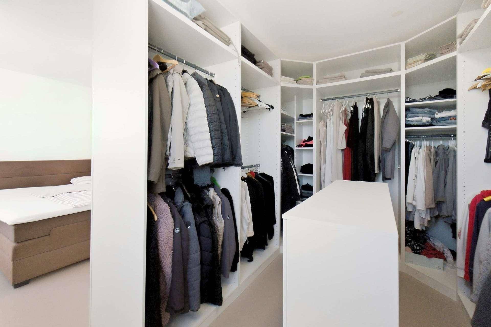 Begehbarer Kleiderschrank mit umfangreichen Aufbewahrungsmöglichkeiten und direktem Zugang zum Schlafzimmer.