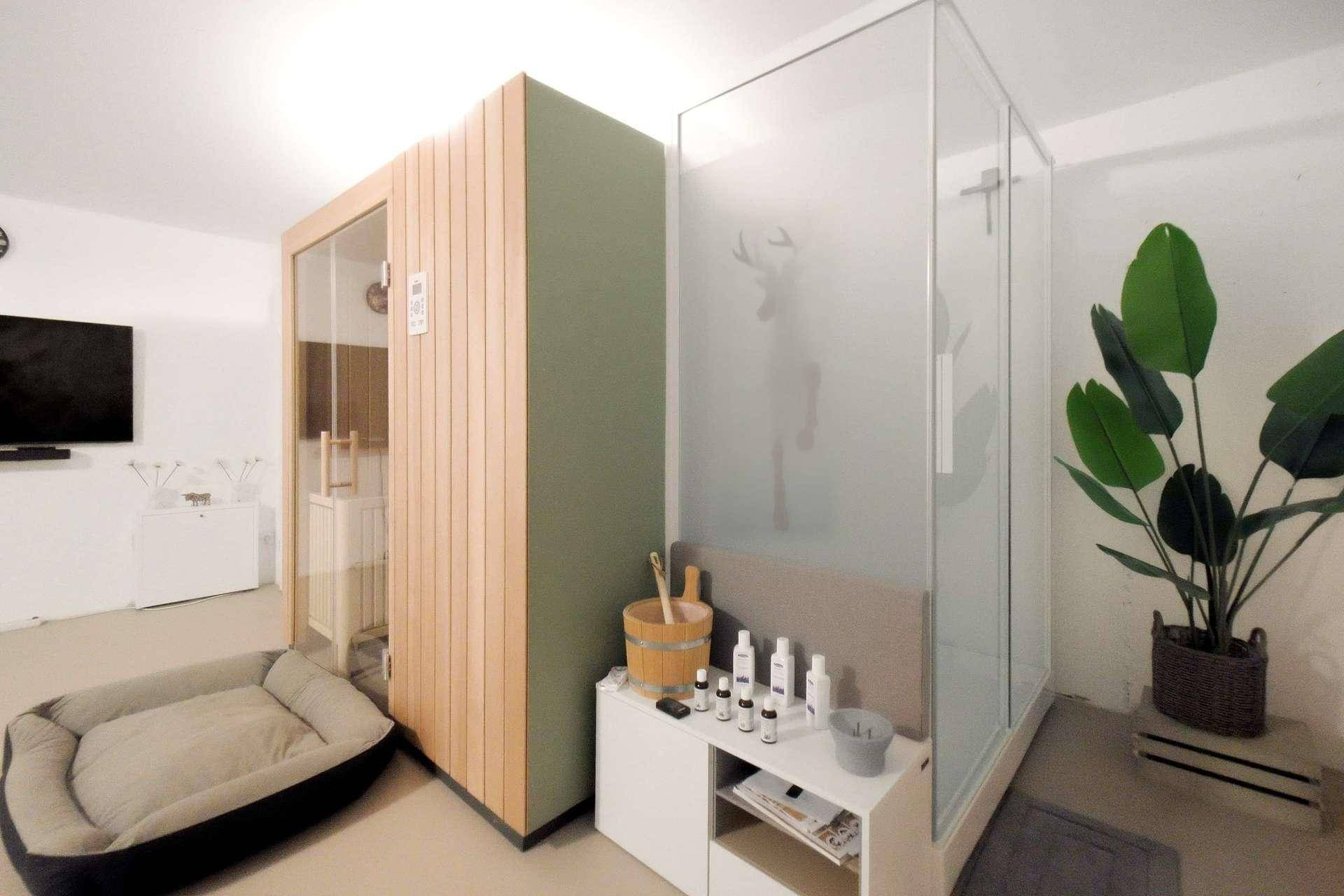 Moderner Wellnessbereich mit Sauna, Glasdusche und hellem Ambiente für Entspannung.