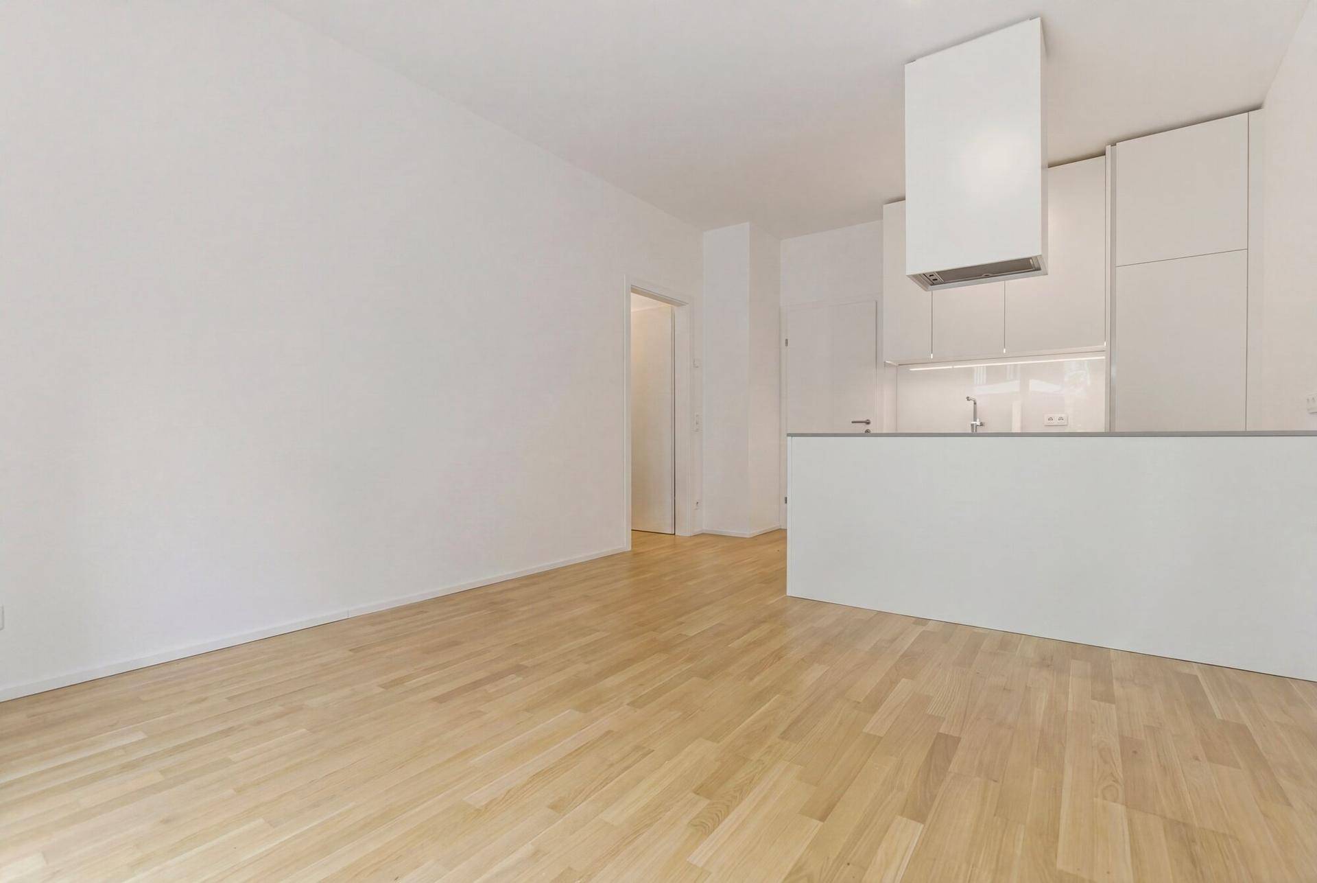 Offener Wohnbereich mit Parkettboden und Blick auf die moderne Küchenzeile.