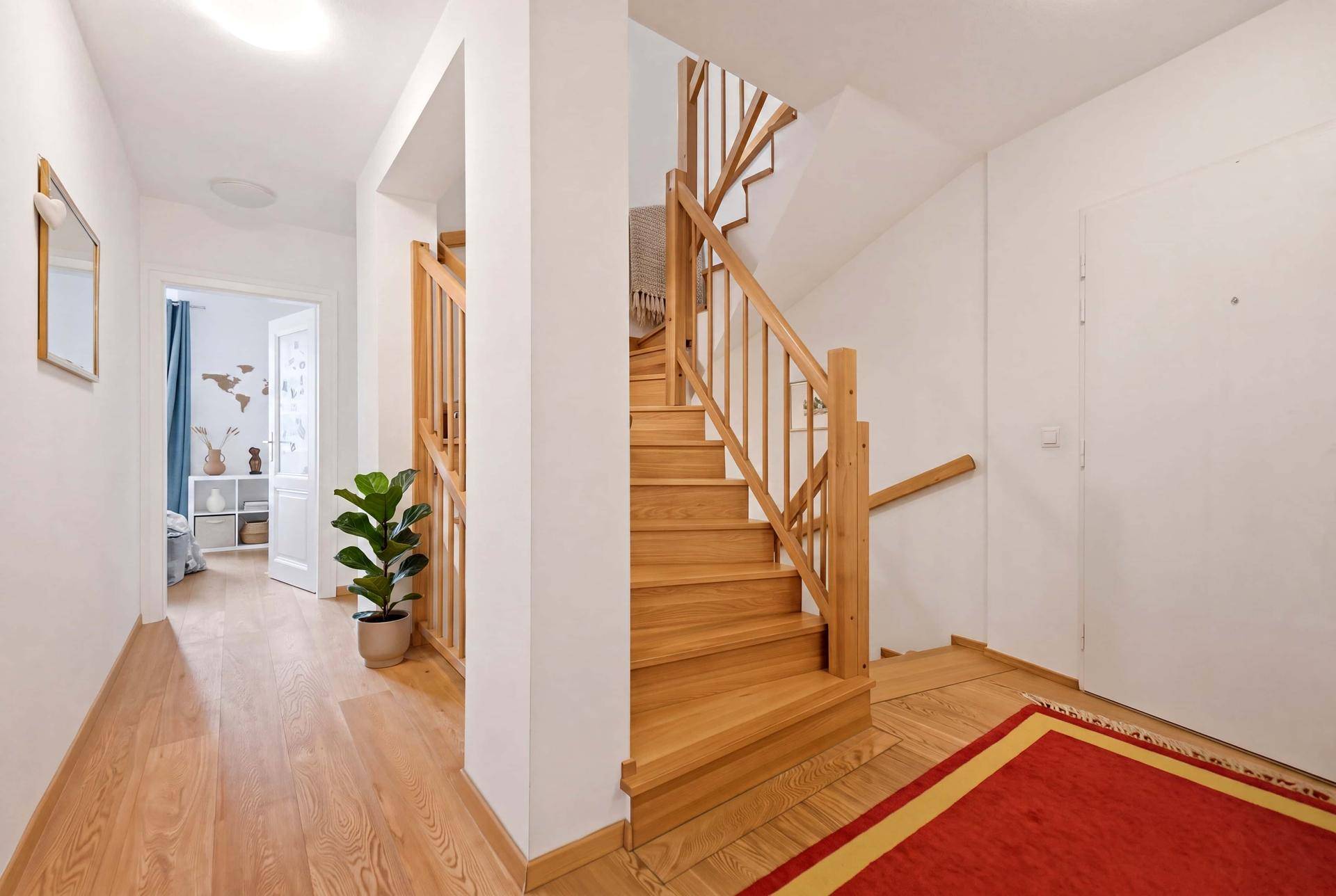 Heller Eingangsbereich mit Holztreppe und Holzboden, einladend und geräumig.
