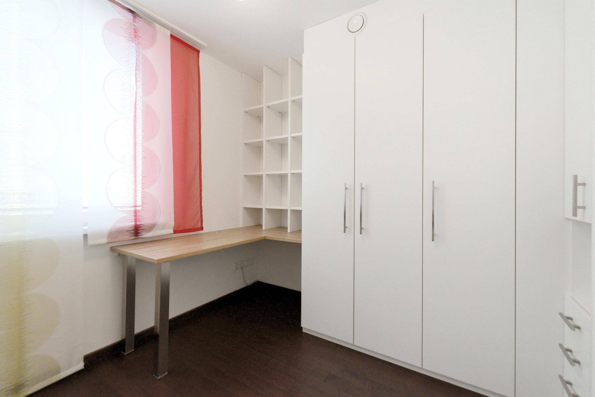 Schlafzimmer mit weißem Einbauschrank und Schreibtisch, ideal für Home-Office oder Studium.