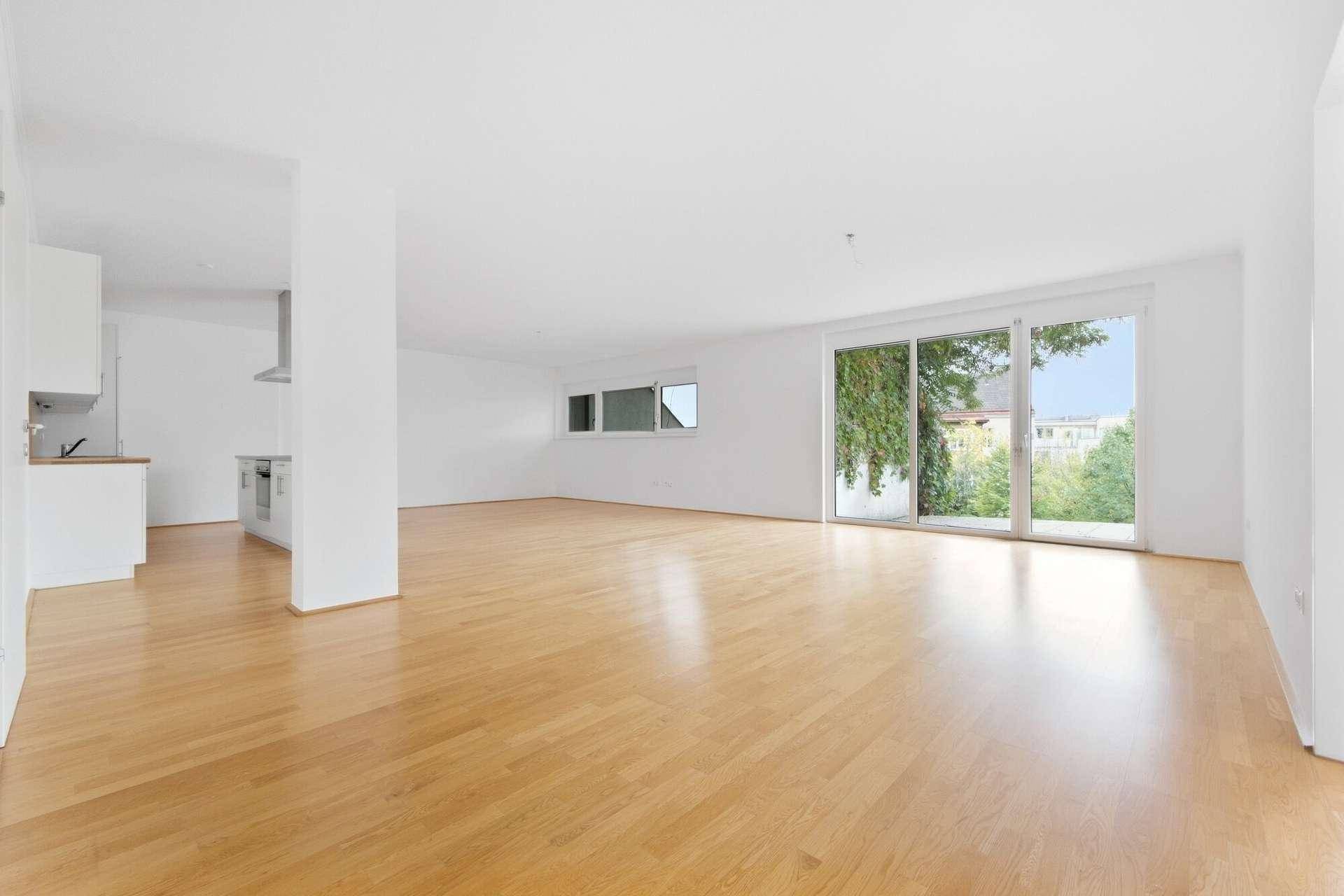 Heller, offener Wohnbereich mit Parkettboden und großen Schiebetüren zur Terrasse.