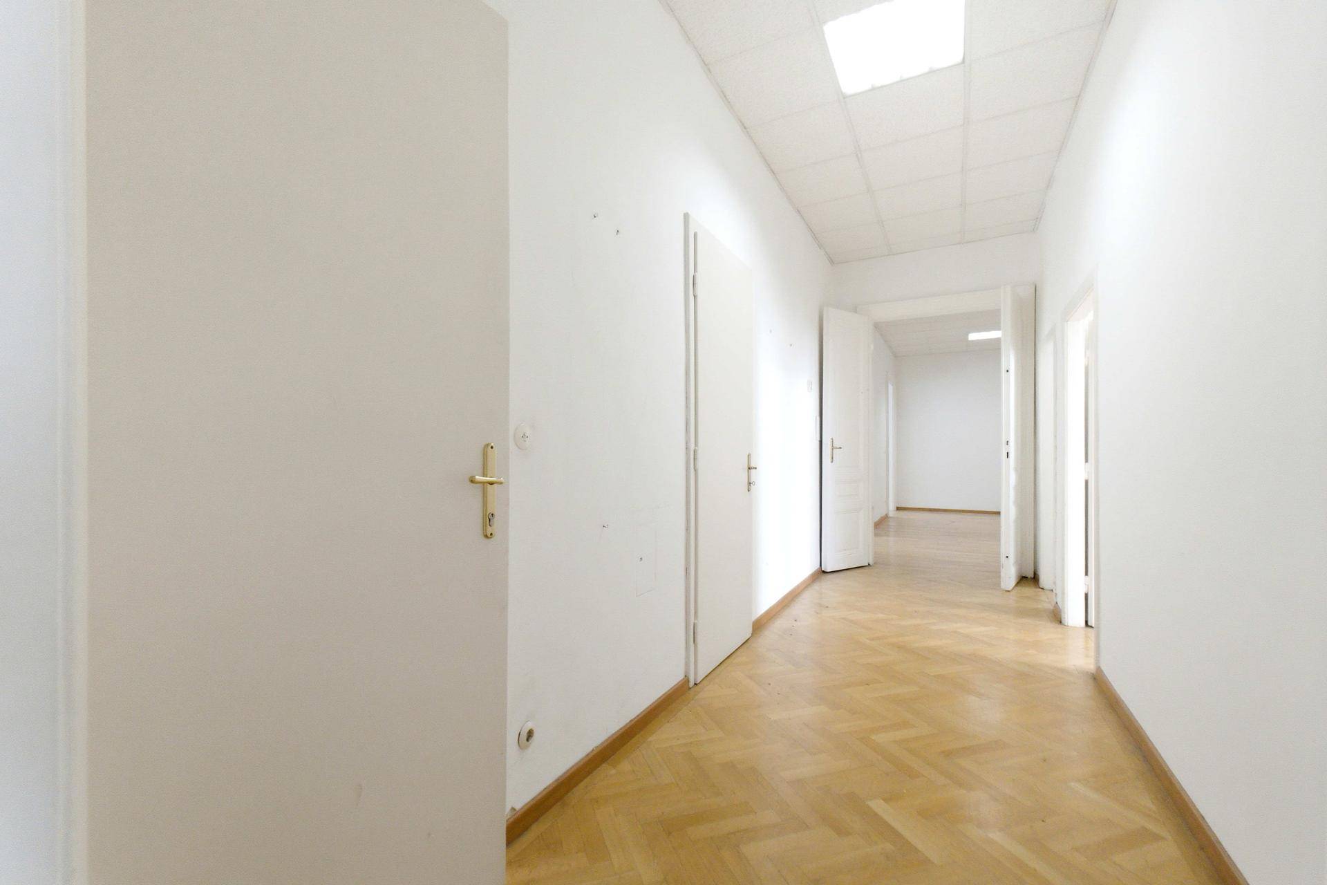 Langer, heller Flur mit Fischgrätparkett und mehreren Türen, führt zu weiteren Räumen.