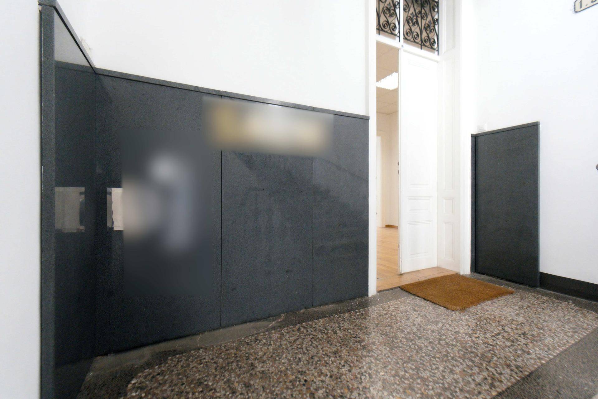 Eingangsbereich einer Wohnung mit dunkler Wandverkleidung und Terrazzoboden.