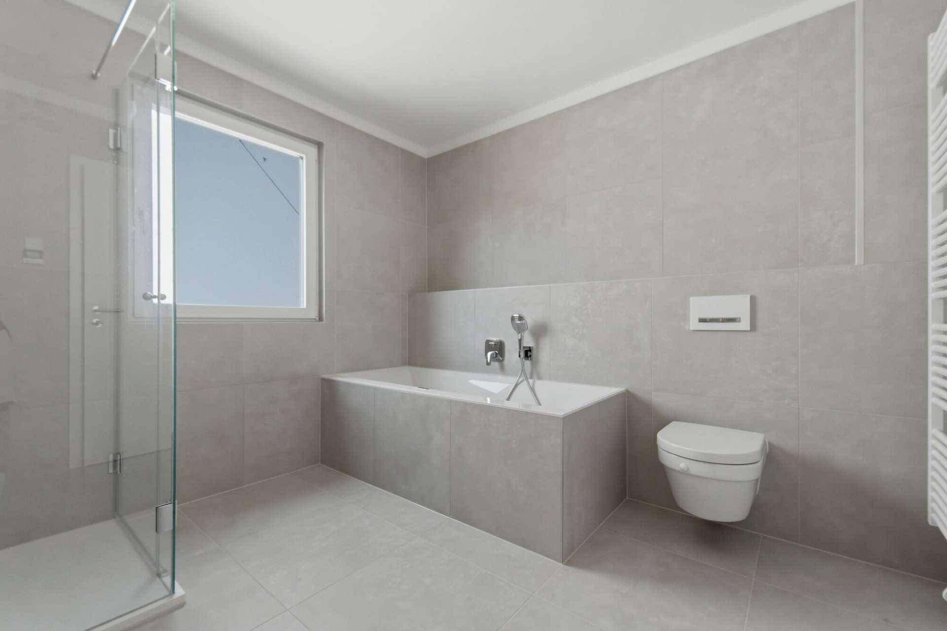 Modernes Badezimmer mit Badewanne, Hänge-WC und begehbarer Dusche, hell gefliest.