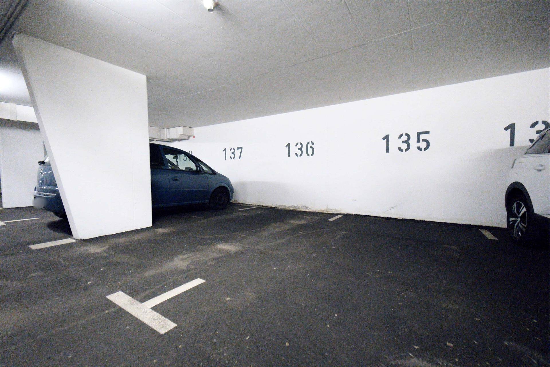 Tiefgaragenstellplatz mit Nummerierung an der Wand und einem blauen Fahrzeug.