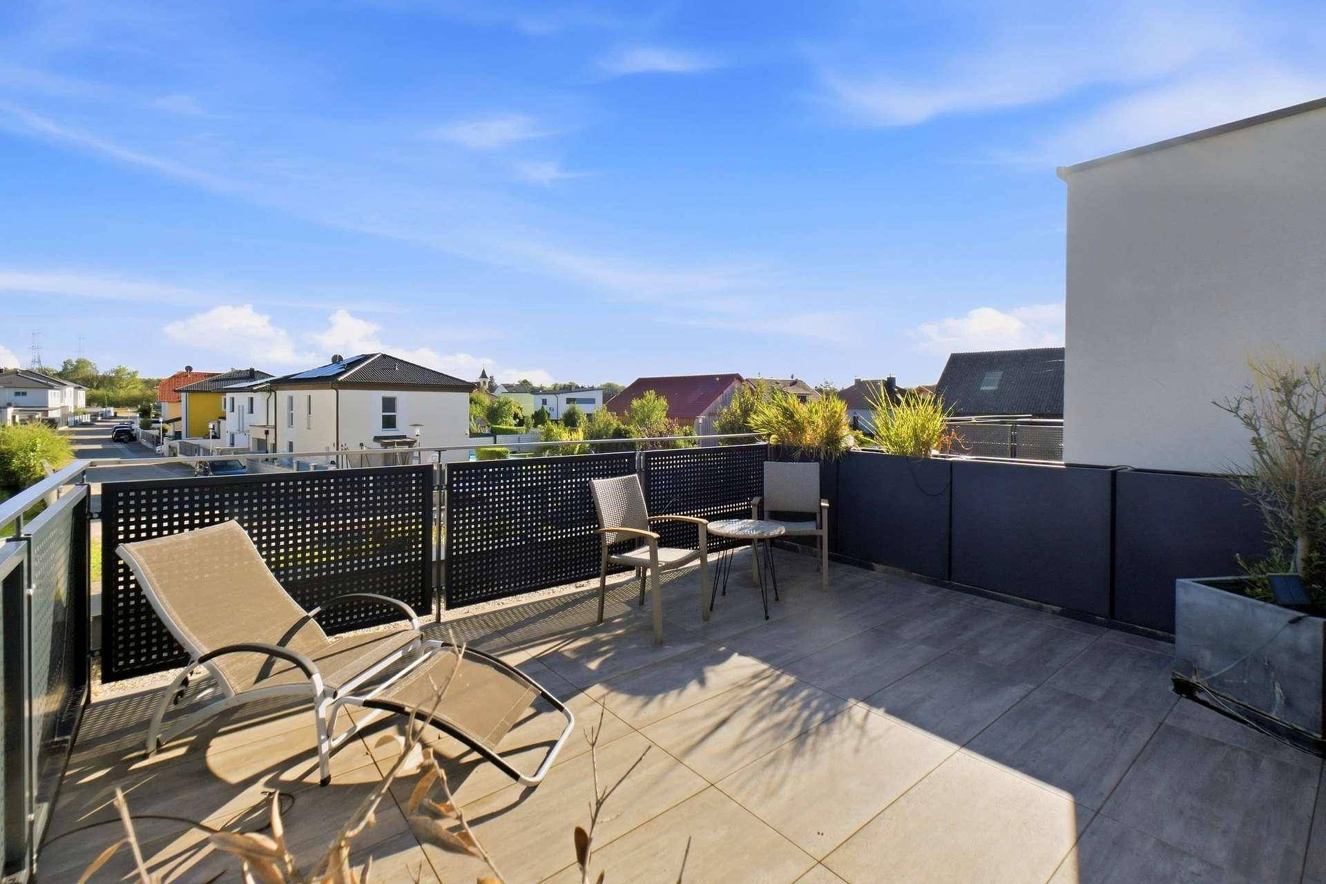 Sonnige Dachterrasse mit Liegestühlen und Blick auf die umliegenden Häuser.