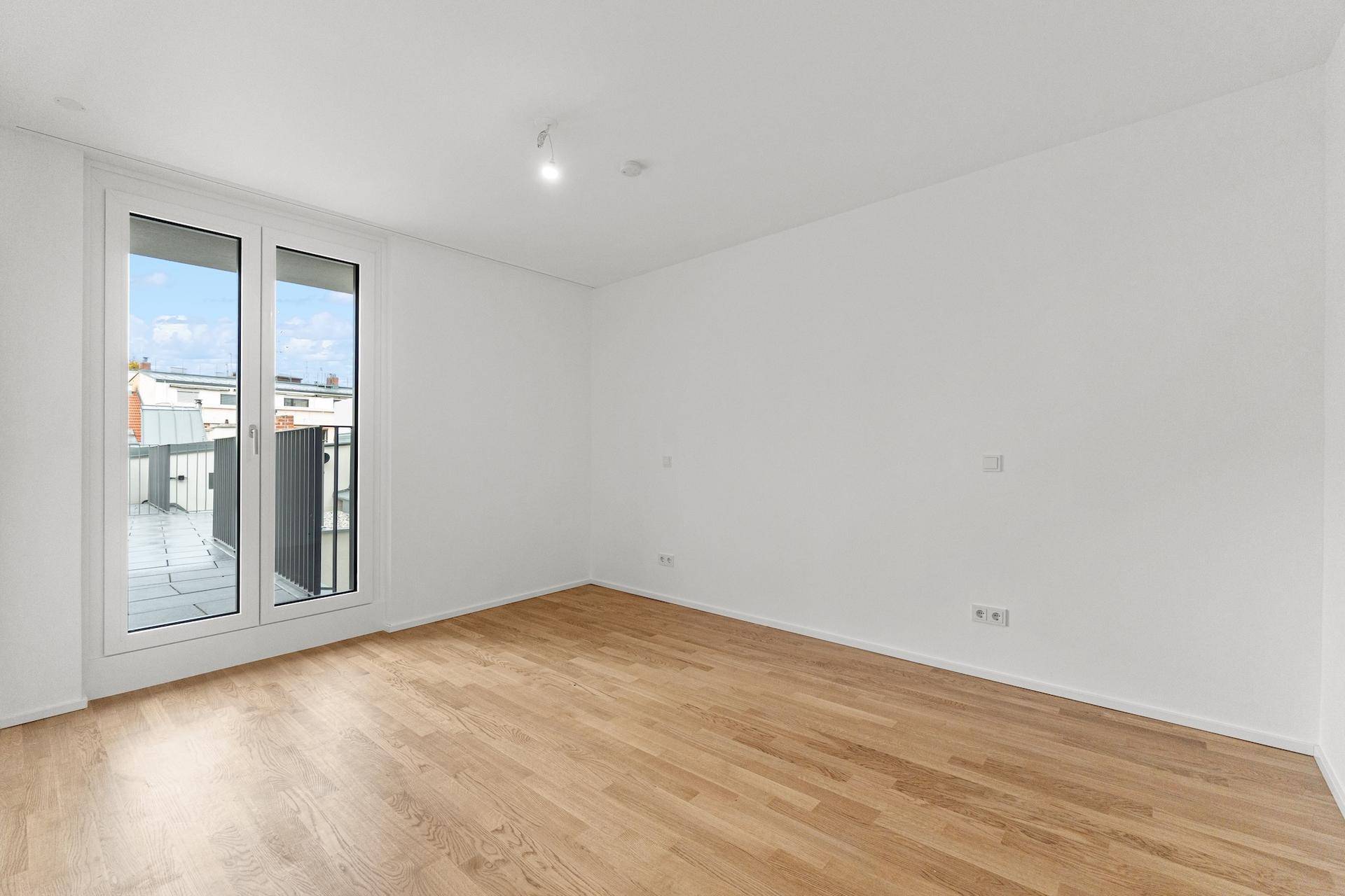 Helles Schlafzimmer mit Holzboden und direktem Zugang zum Balkon.