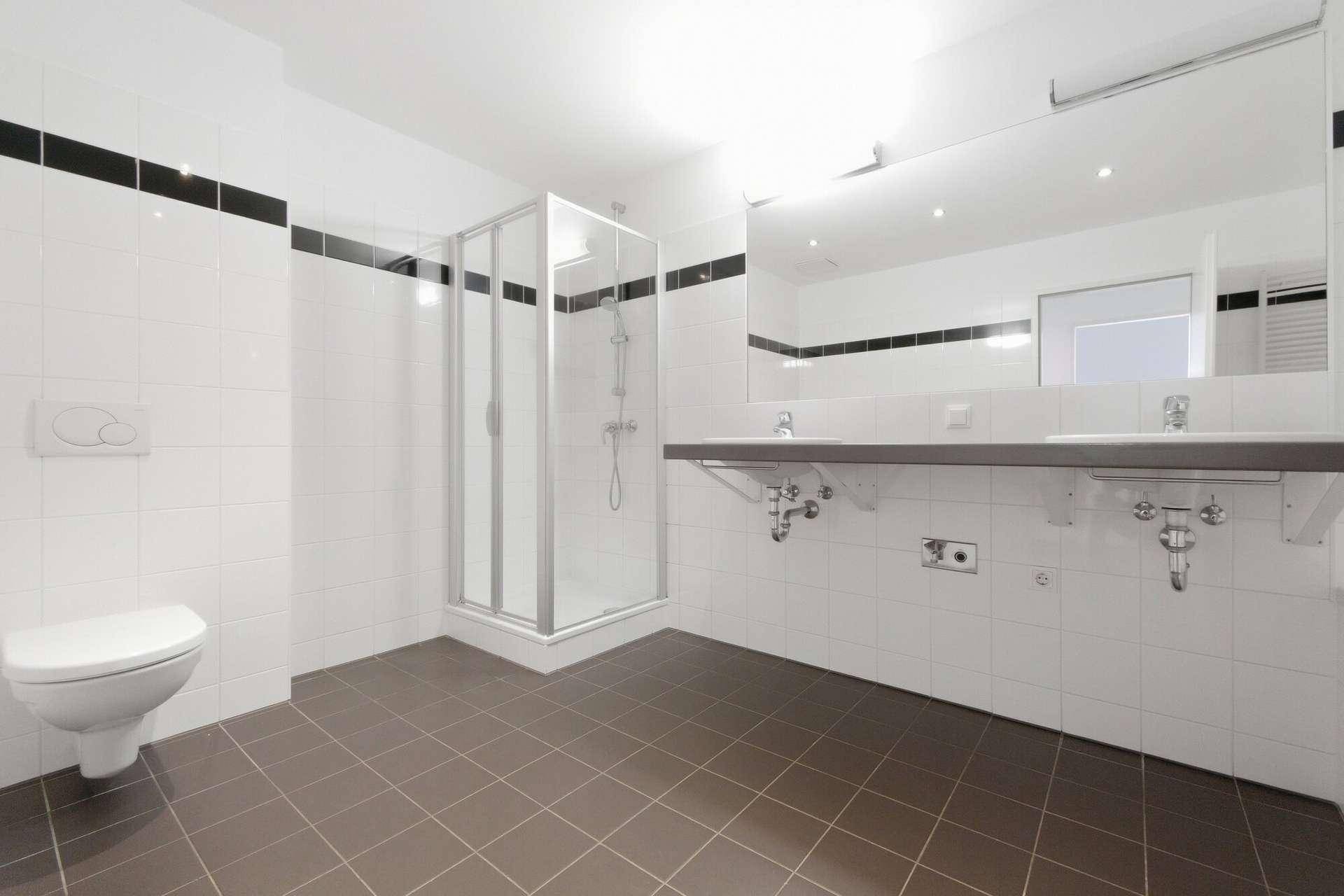 Modernes Badezimmer mit Dusche, Doppelwaschbecken und Wand-WC in Weiß und Grau.