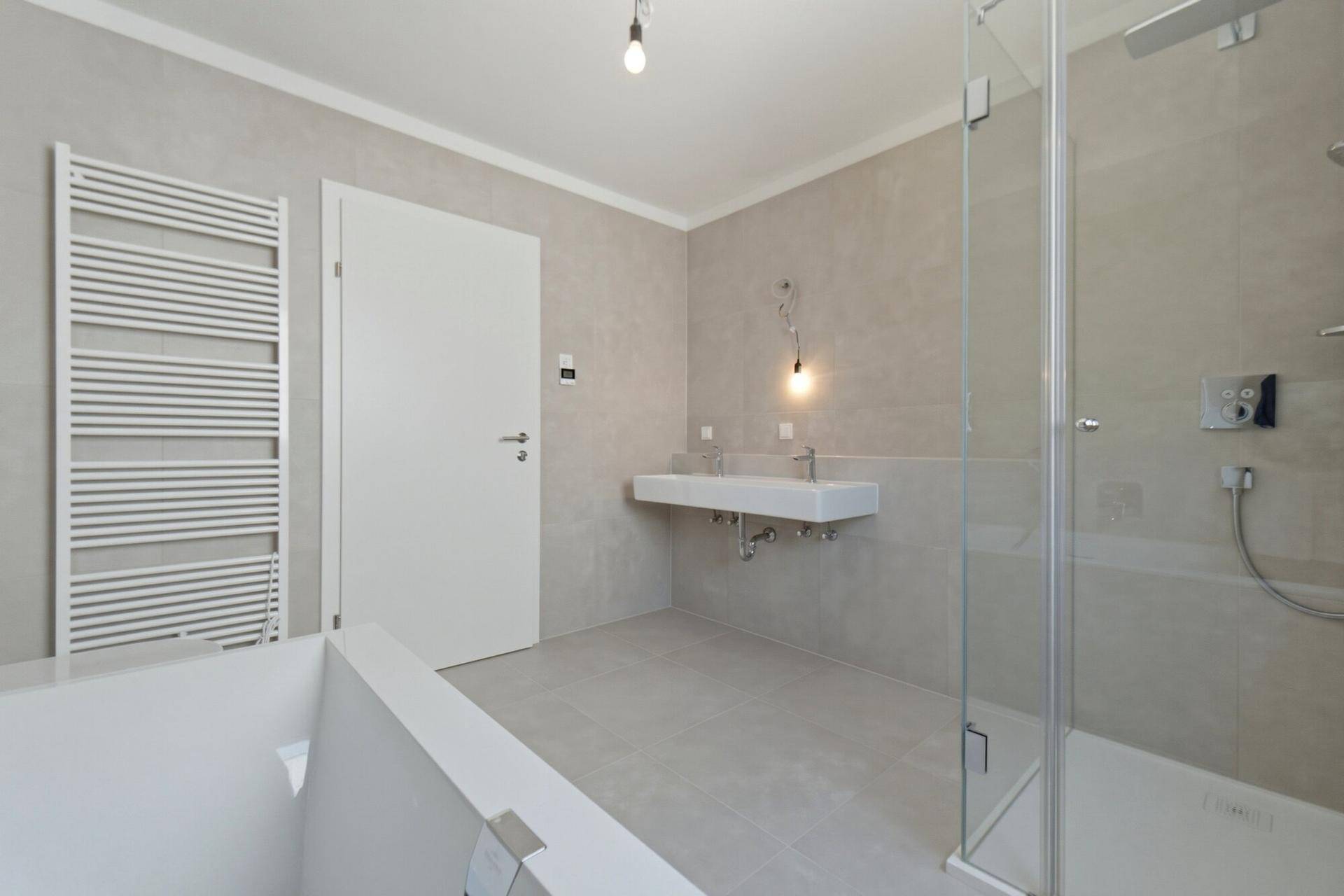 Modernes Badezimmer mit Dusche, Doppelwaschbecken, beheiztem Handtuchhalter und Badewanne.